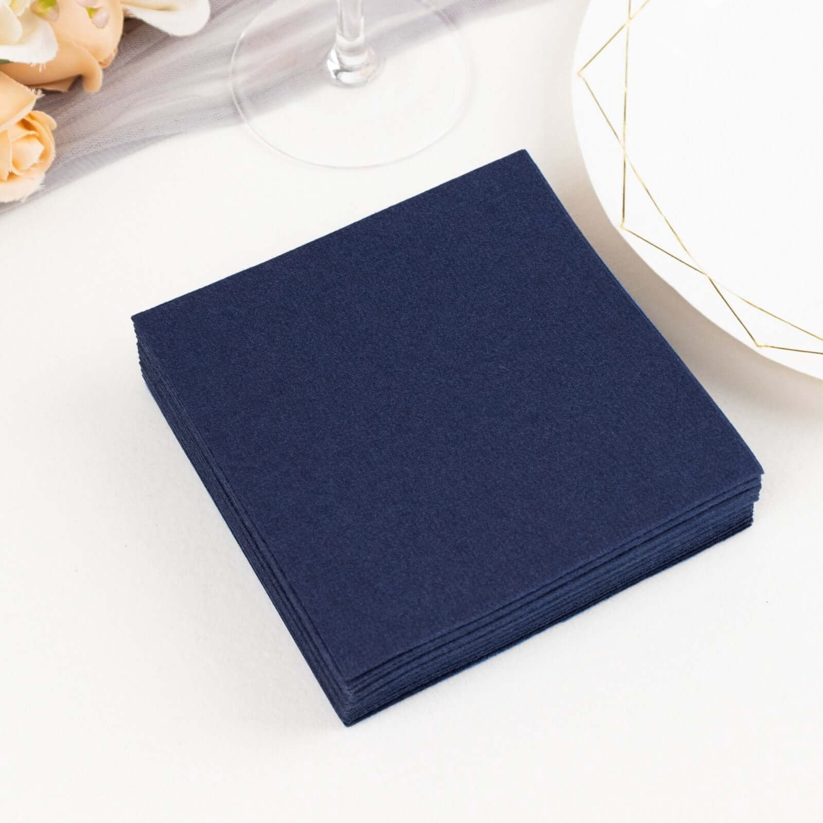 Navy blue linen-feel cocktail napkins stacked on a table.