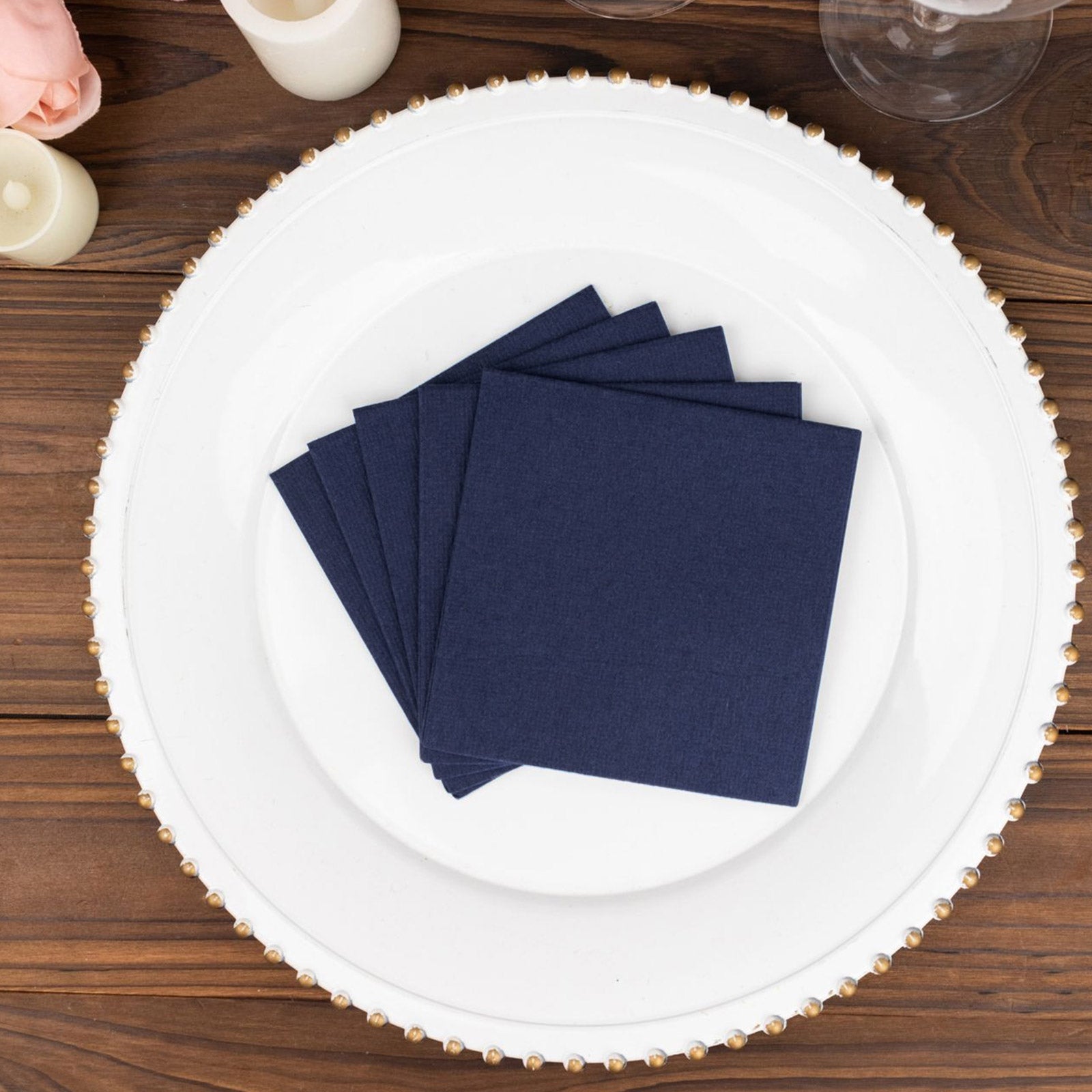 Navy blue linen-feel cocktail napkins on a decorative plate.