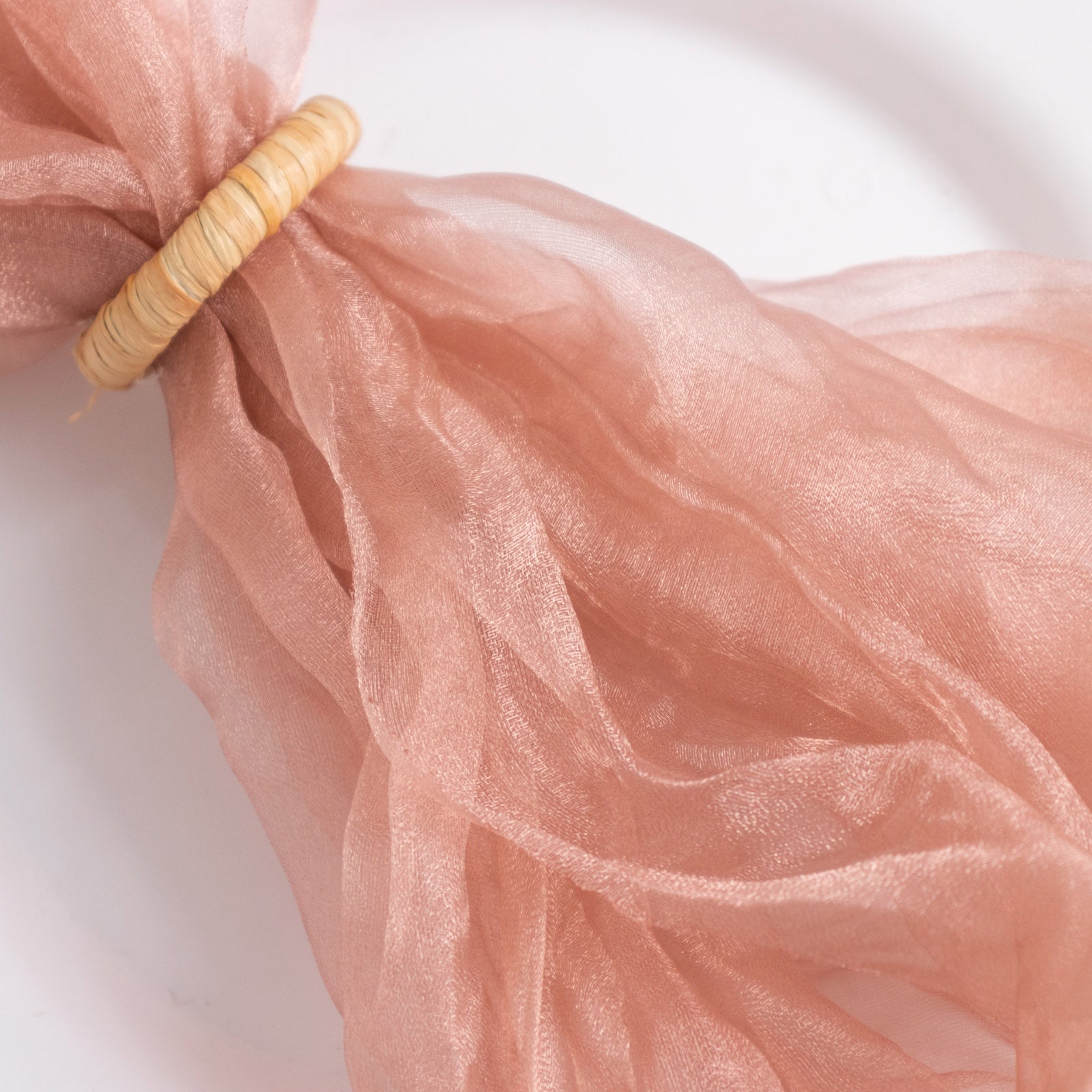 Dusty rose sheer crinkled organza dinner napkin with a decorative ring.