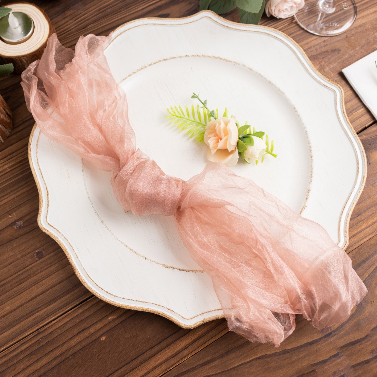 Dusty rose sheer crinkled organza napkin on a decorative plate.