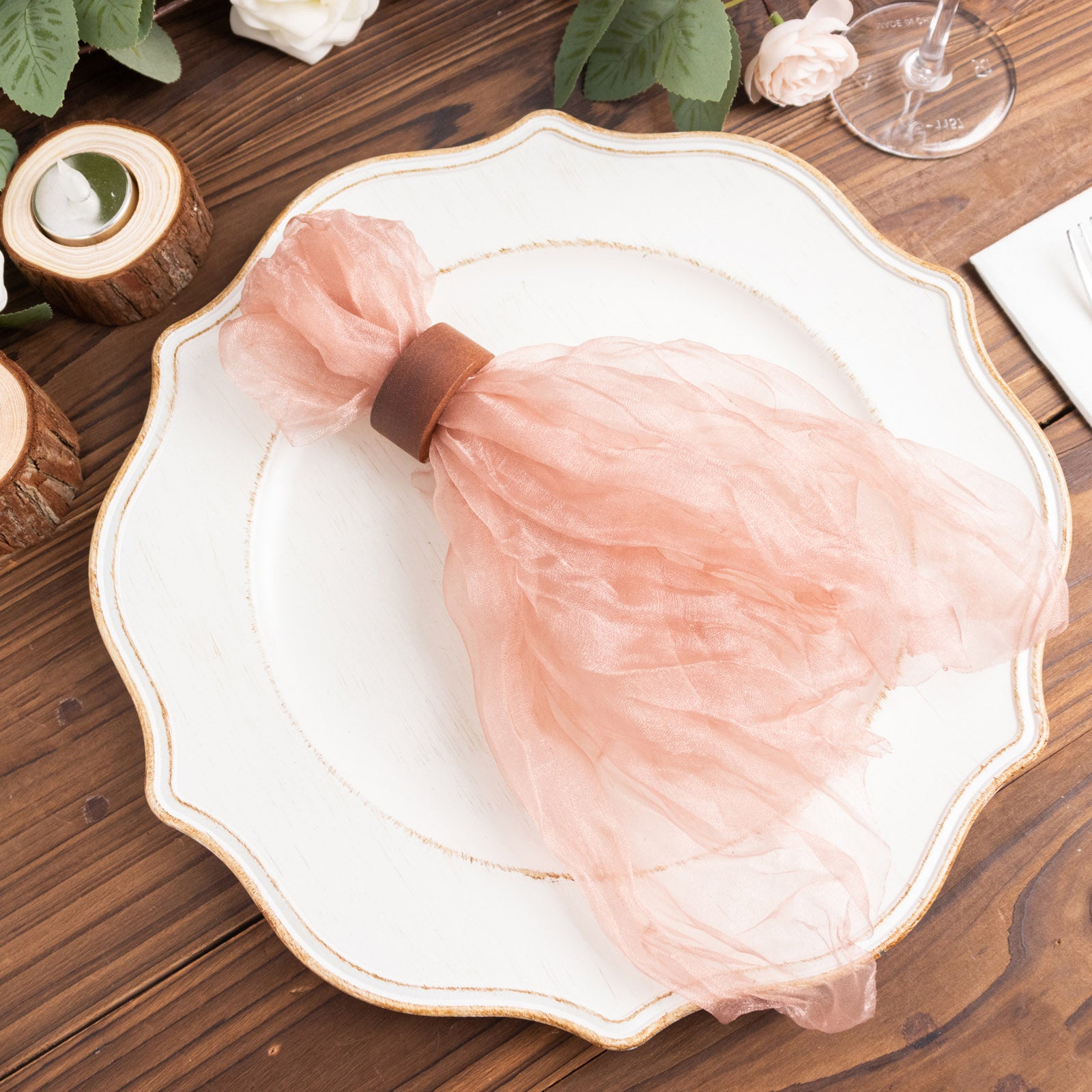 Dusty rose sheer crinkled organza dinner napkin on a decorative plate.
