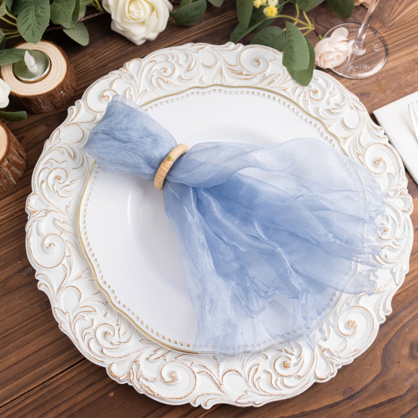 Dusty blue sheer crinkled organza dinner napkin on a decorative plate.