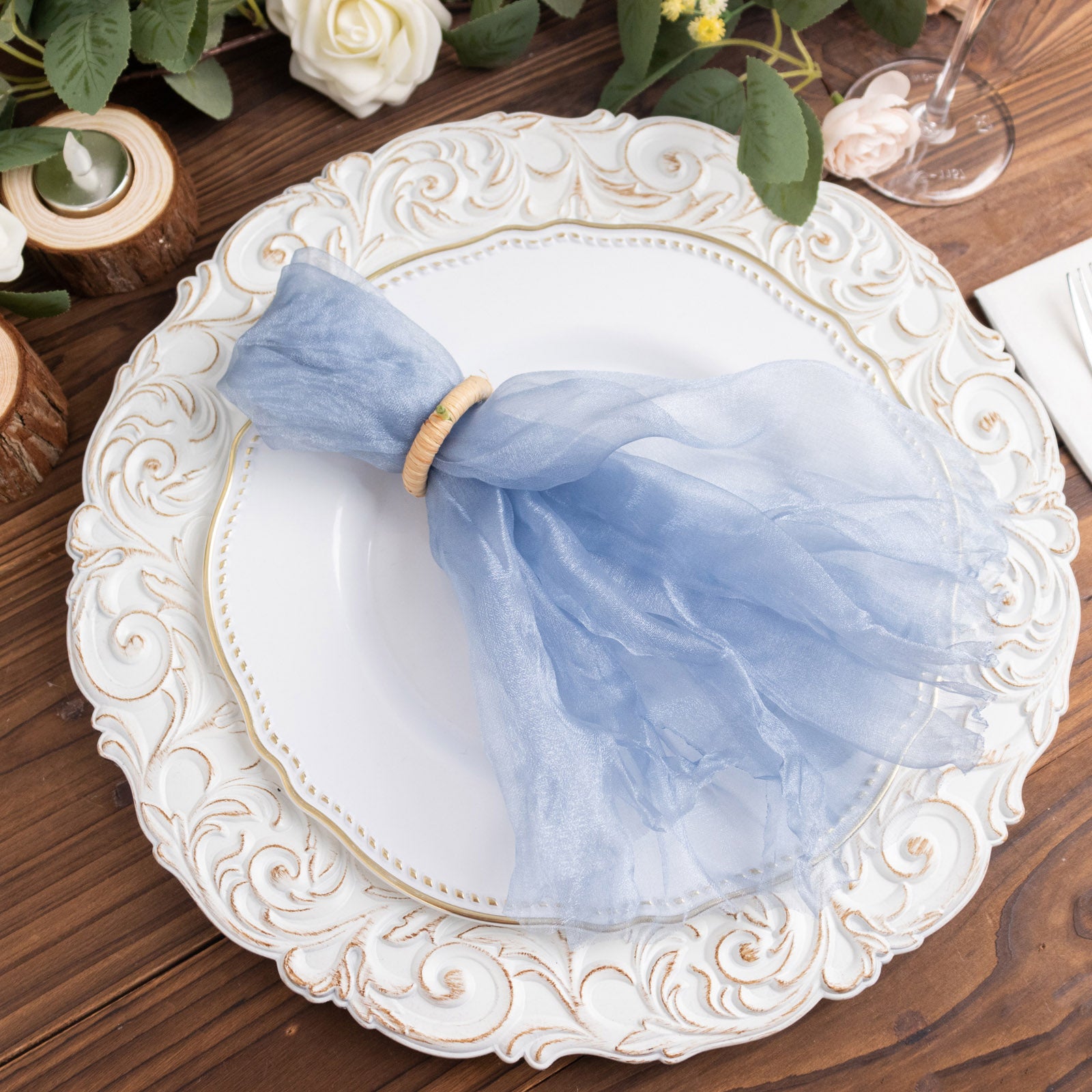 Dusty blue sheer crinkled organza dinner napkin on a decorative plate.