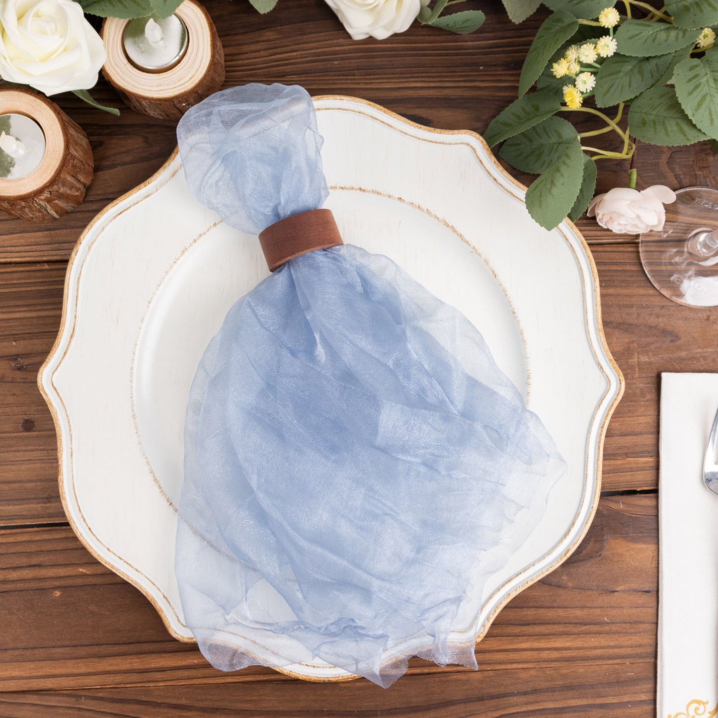Dusty blue sheer crinkled organza dinner napkin on a white plate.