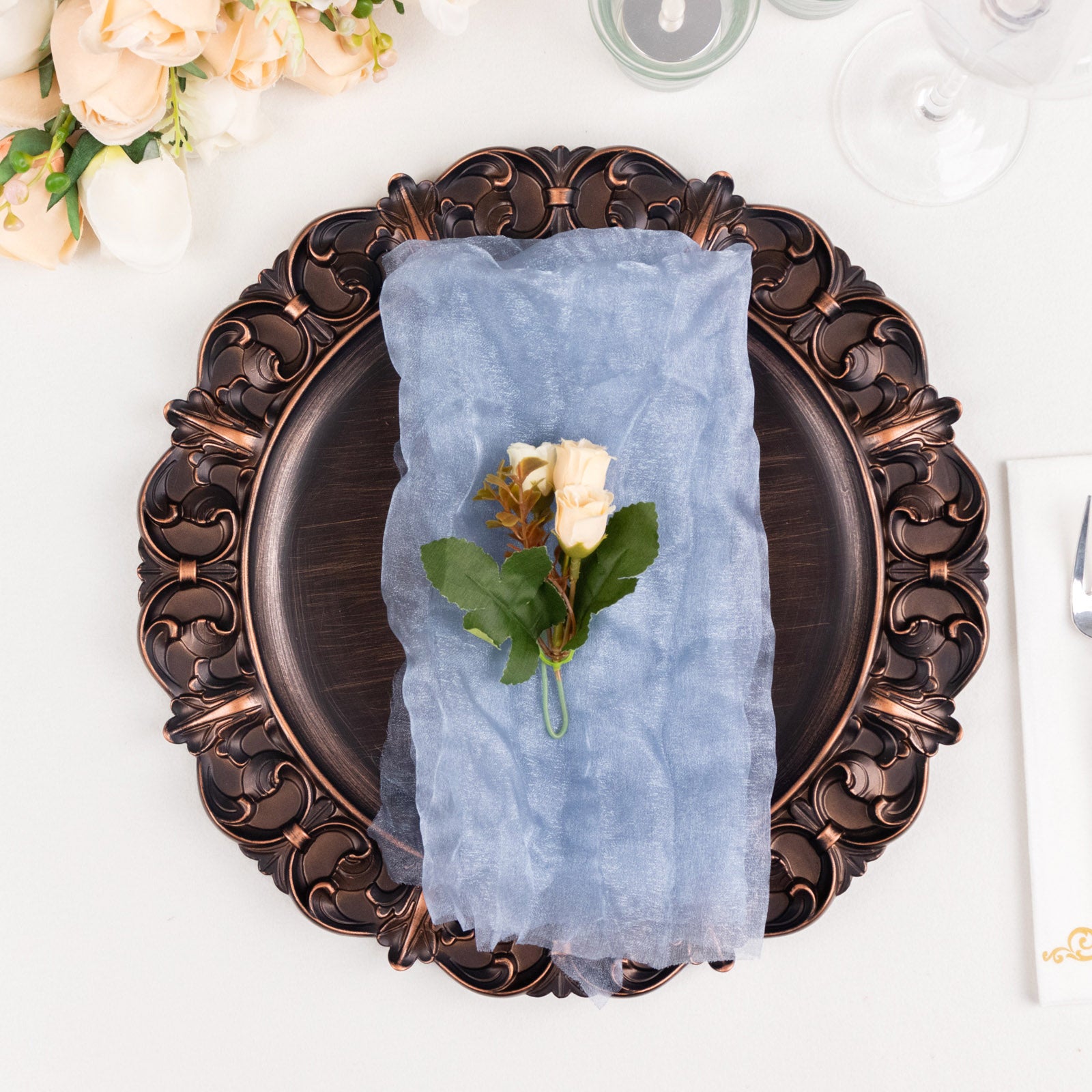 Dusty blue sheer crinkled organza dinner napkin on ornate plate.