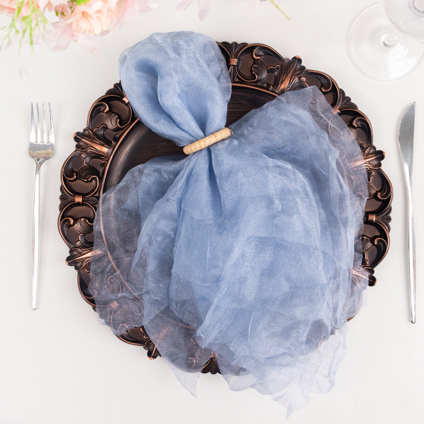 Dusty blue sheer crinkled organza dinner napkin on an ornate plate.