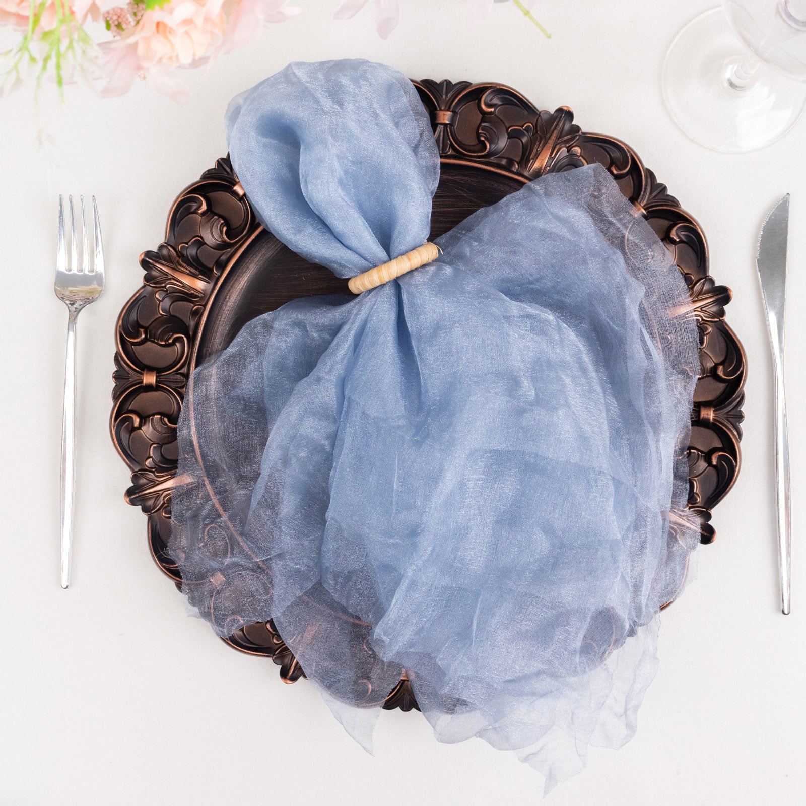 Dusty blue sheer crinkled organza dinner napkin on an ornate plate.