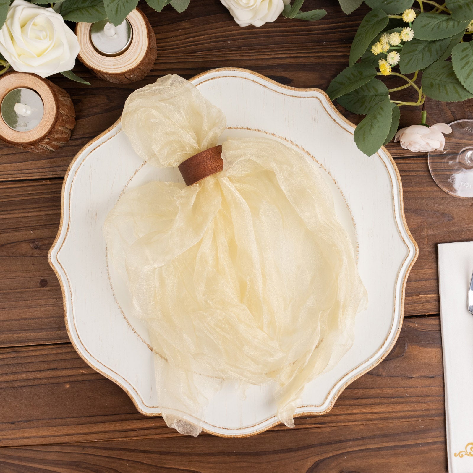 Champagne sheer crinkled organza dinner napkin on a decorative plate.