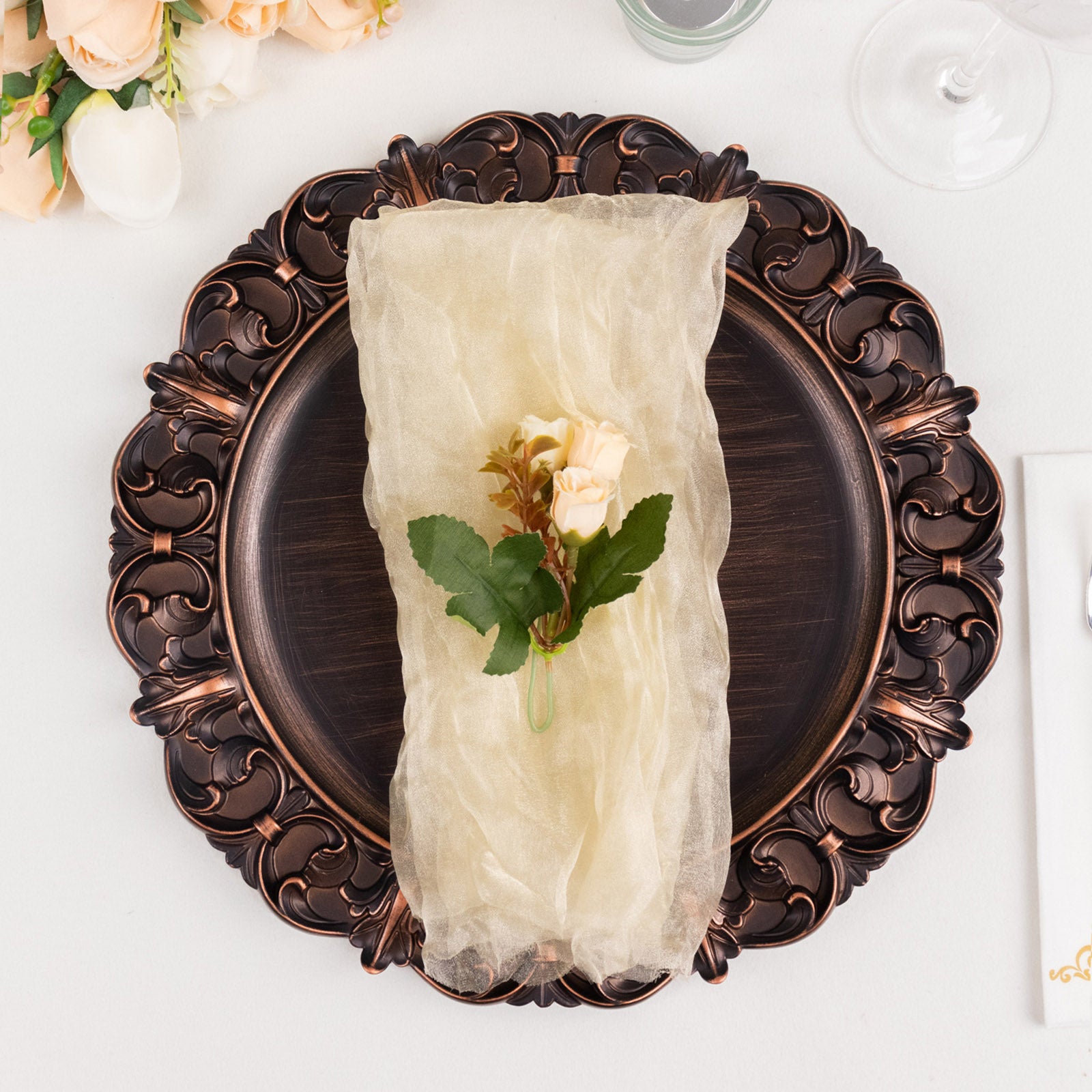 Champagne sheer crinkled organza dinner napkin on a decorative plate.