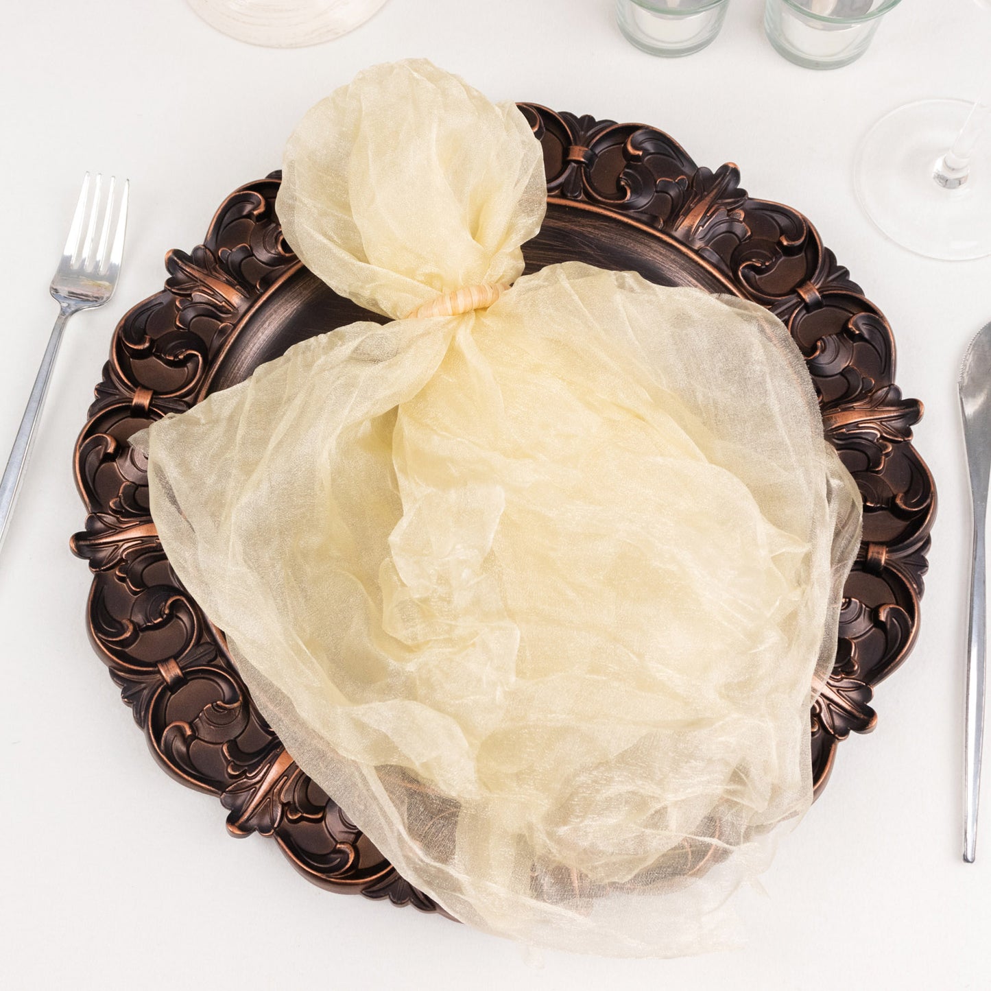 Champagne sheer crinkled organza dinner napkin on an elegant plate.