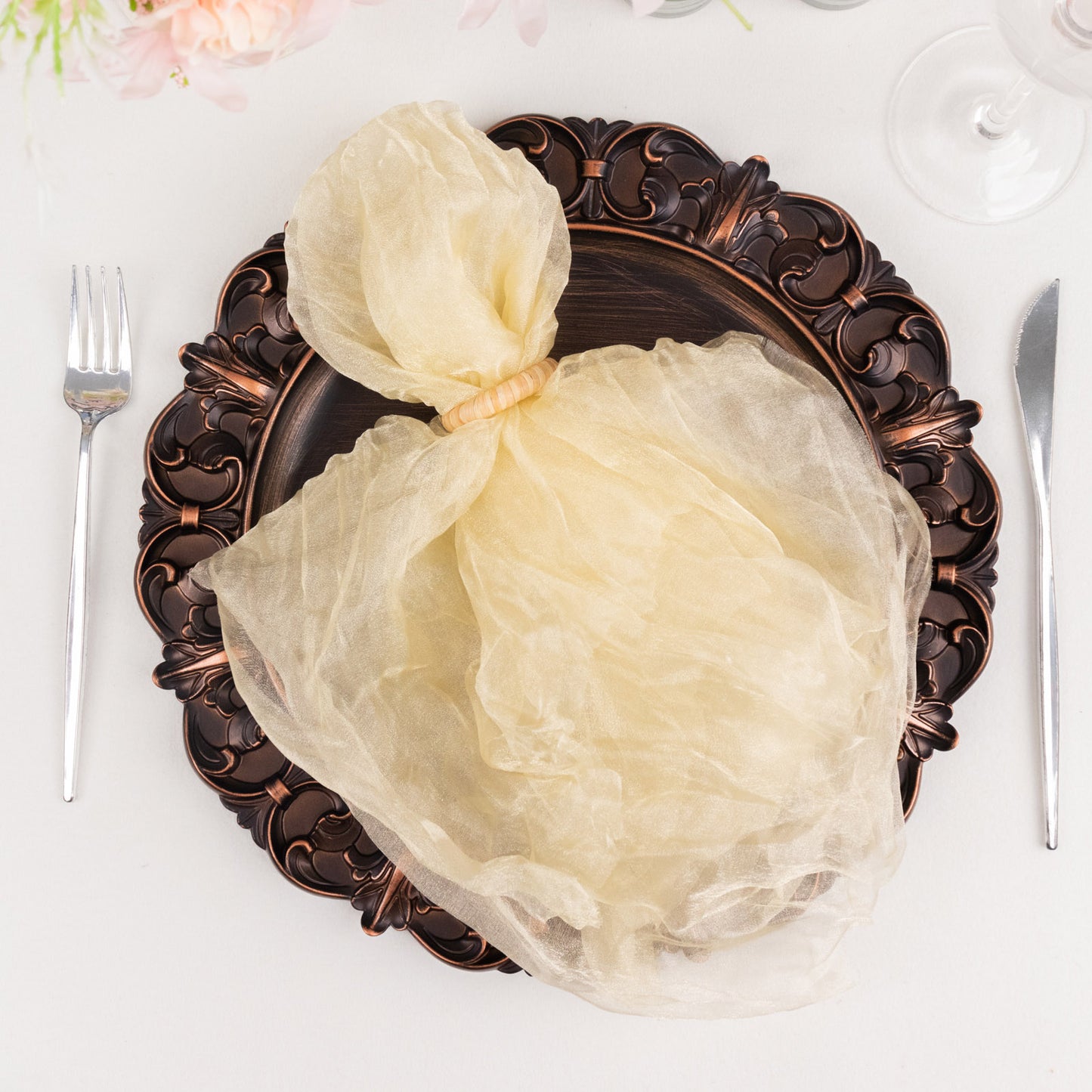Champagne sheer crinkled organza dinner napkin on an ornate plate.