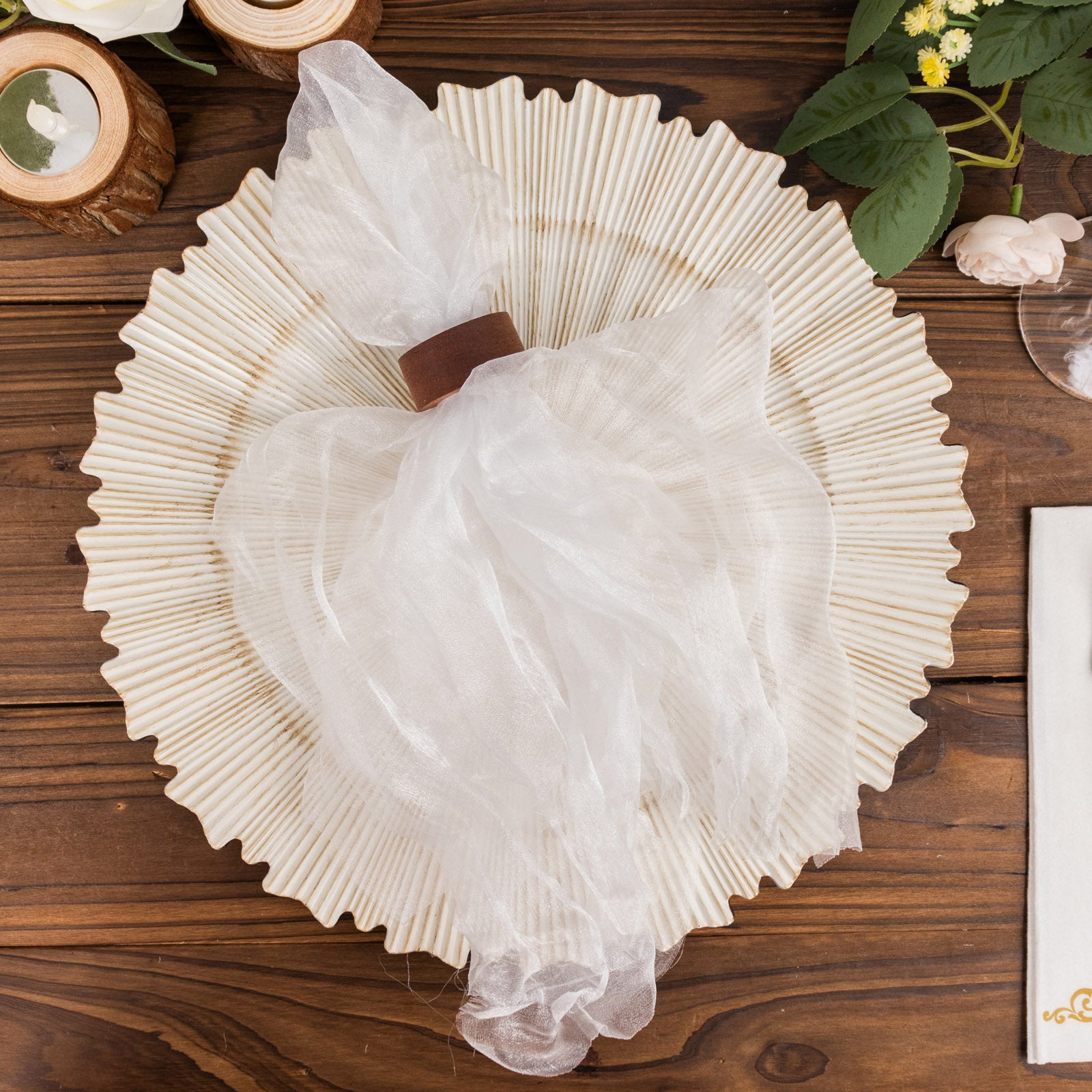 White sheer crinkled organza dinner napkin on a decorative plate.