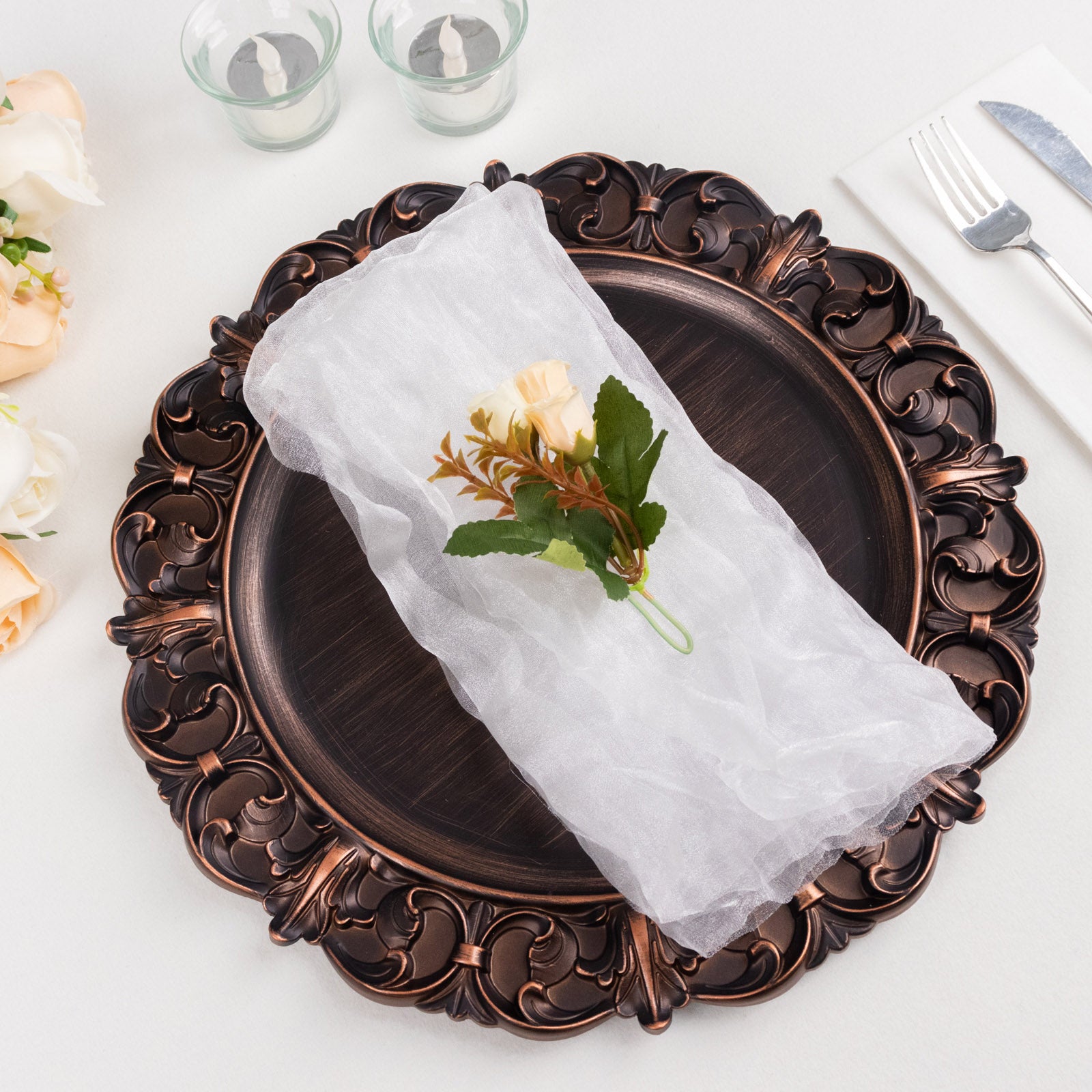 White sheer crinkled organza dinner napkin on an ornate plate.