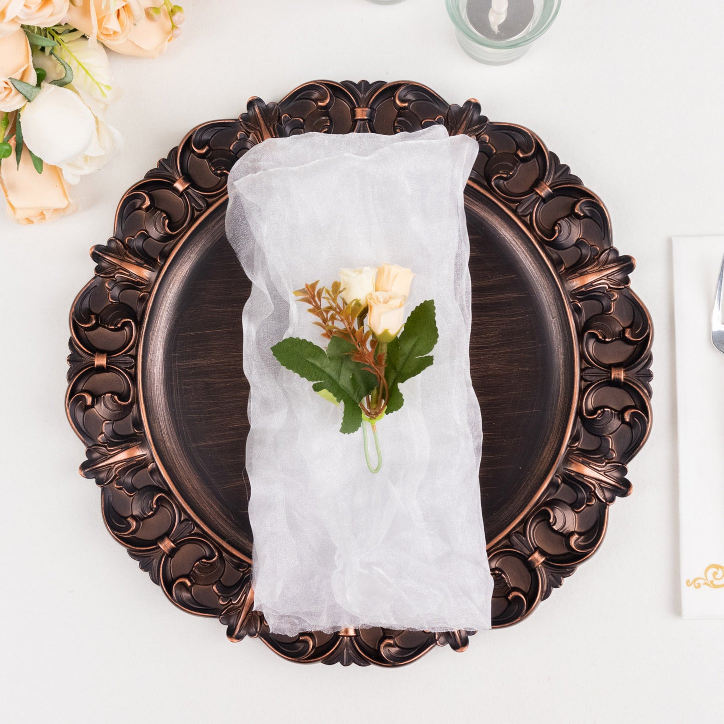 White sheer crinkled organza dinner napkin with floral decoration on a decorative plate.