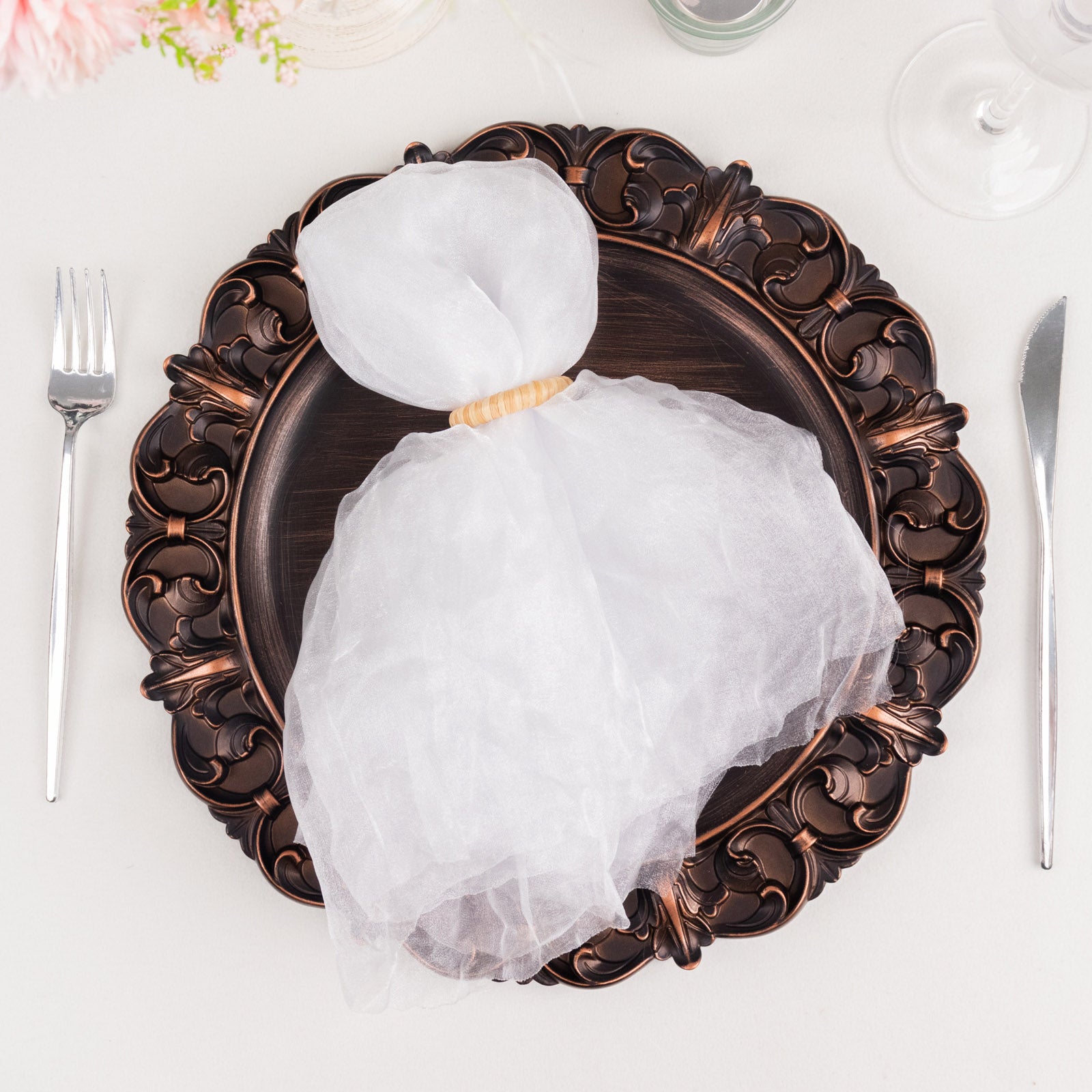 White sheer crinkled organza dinner napkin on an ornate plate.
