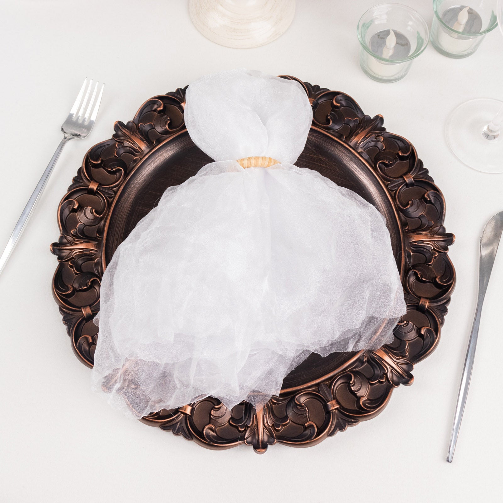 White sheer crinkled organza dinner napkin on an ornate plate.