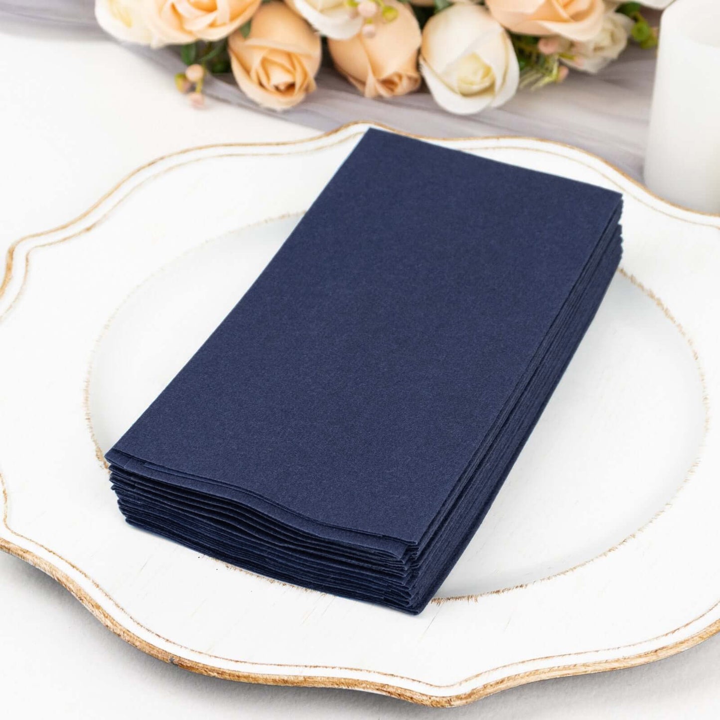Navy blue linen-feel disposable paper napkins stacked on a white plate.