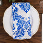 Royal blue and white damask taffeta napkin on a decorative plate.