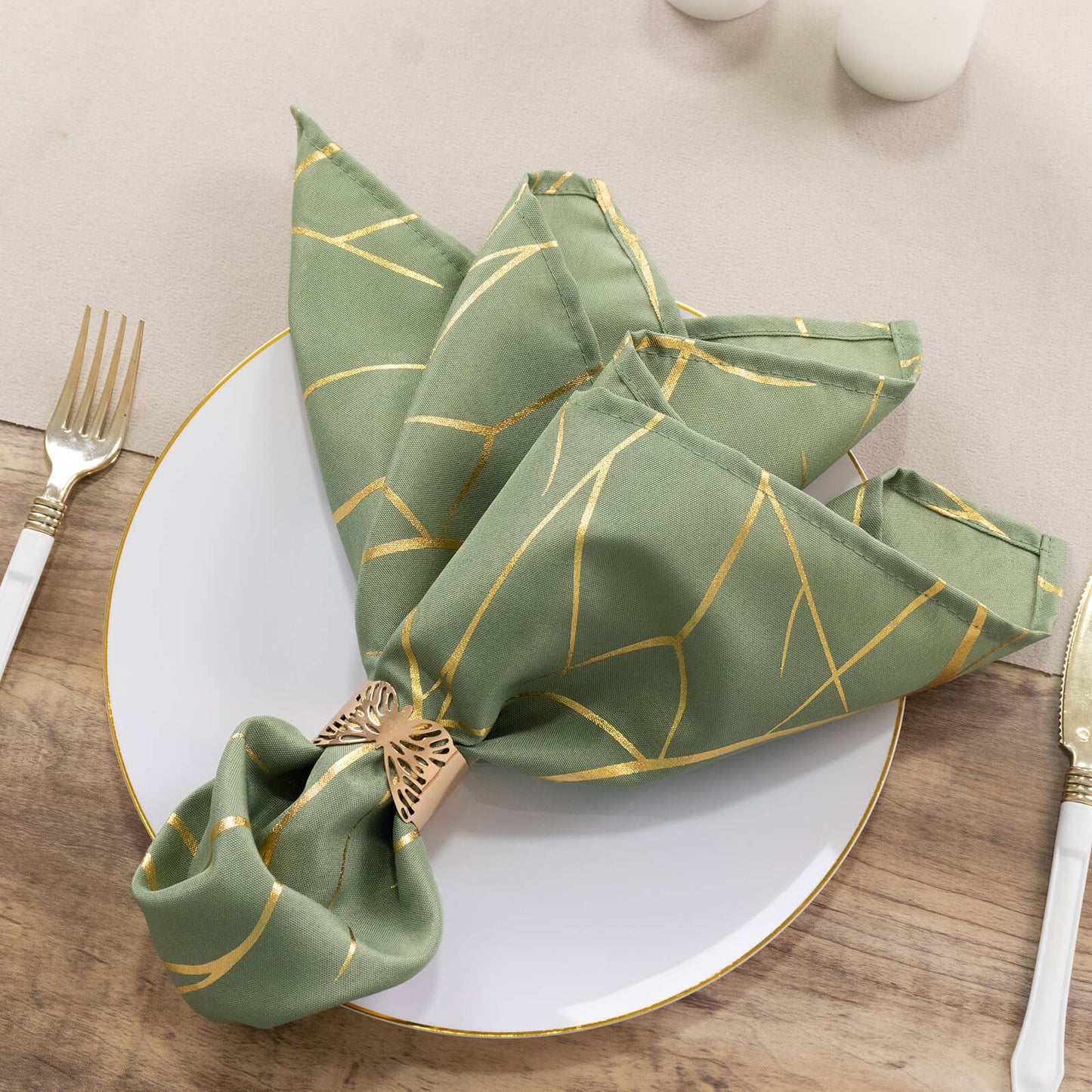 Dusty sage green napkin with gold foil tree branch pattern on a plate.