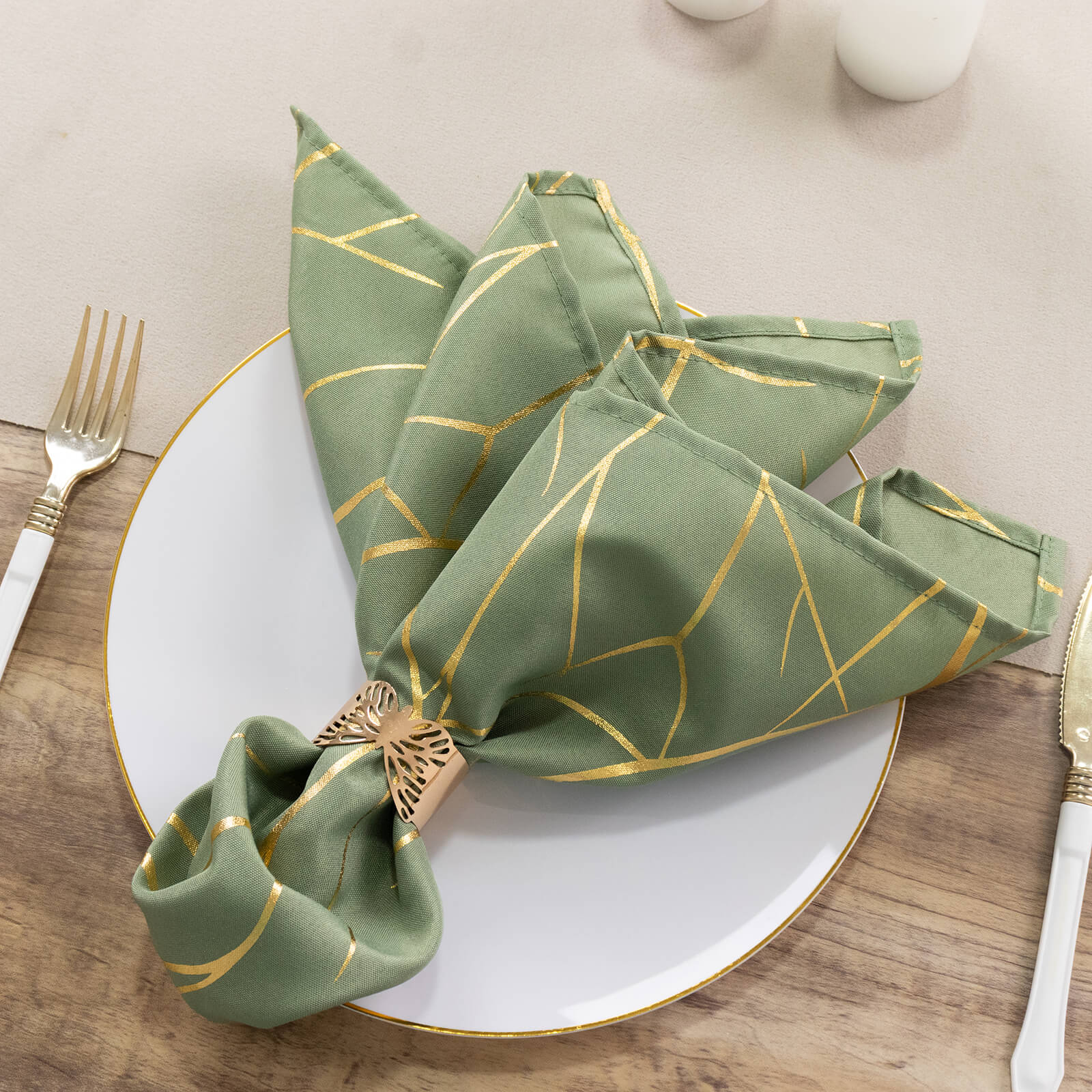 Dusty sage green napkin with gold foil tree branch pattern on a plate.