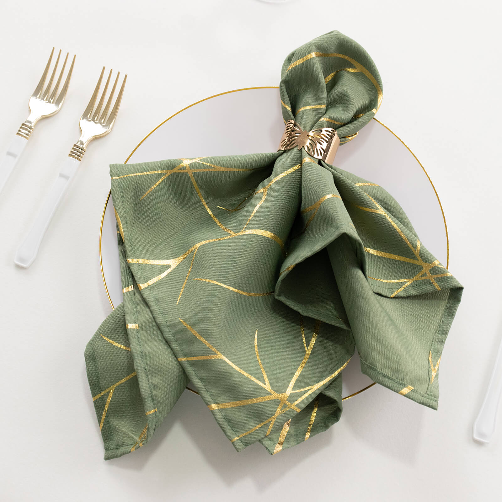 Dusty sage green napkin with gold foil tree branch pattern on a plate.