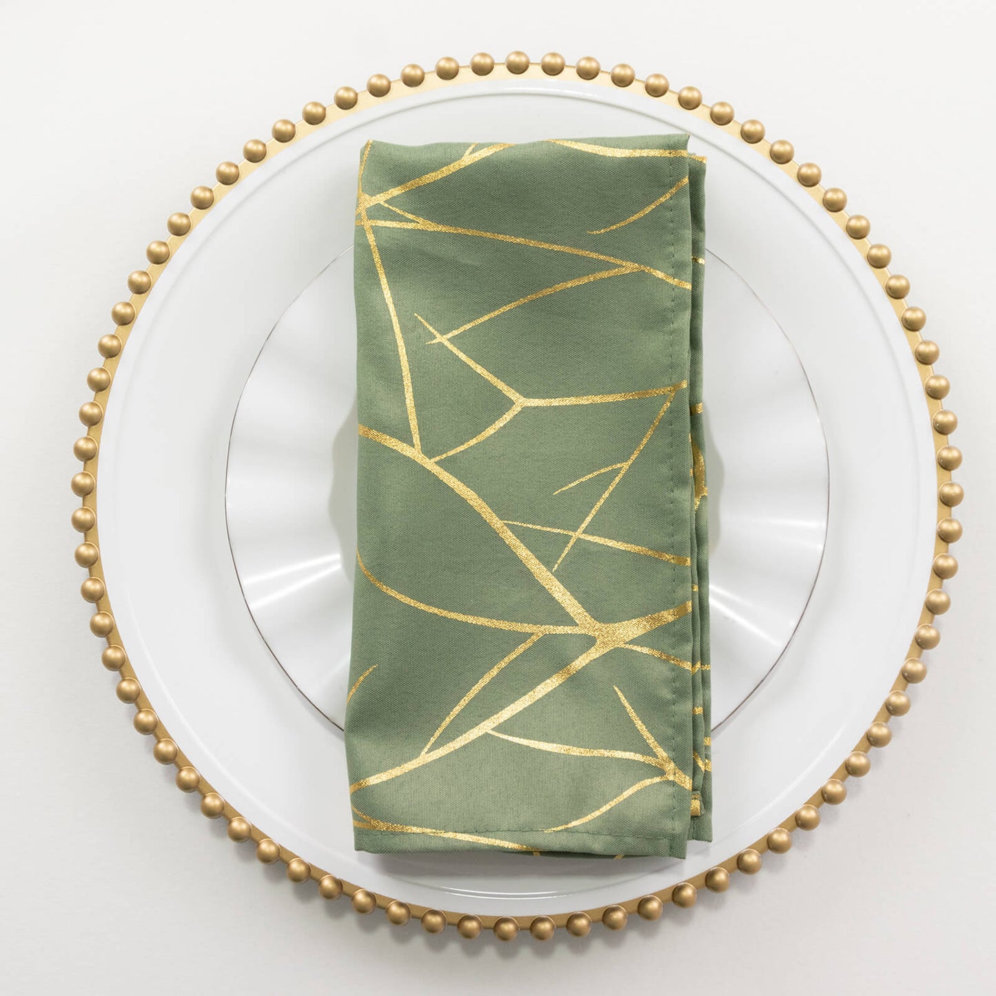 Dusty sage green dinner napkin with gold foil tree branch pattern.