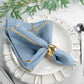 Modern dusty blue and geometric gold cloth dinner napkin on a white plate.