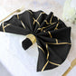 Modern black and geometric gold dinner napkin on a table setting.