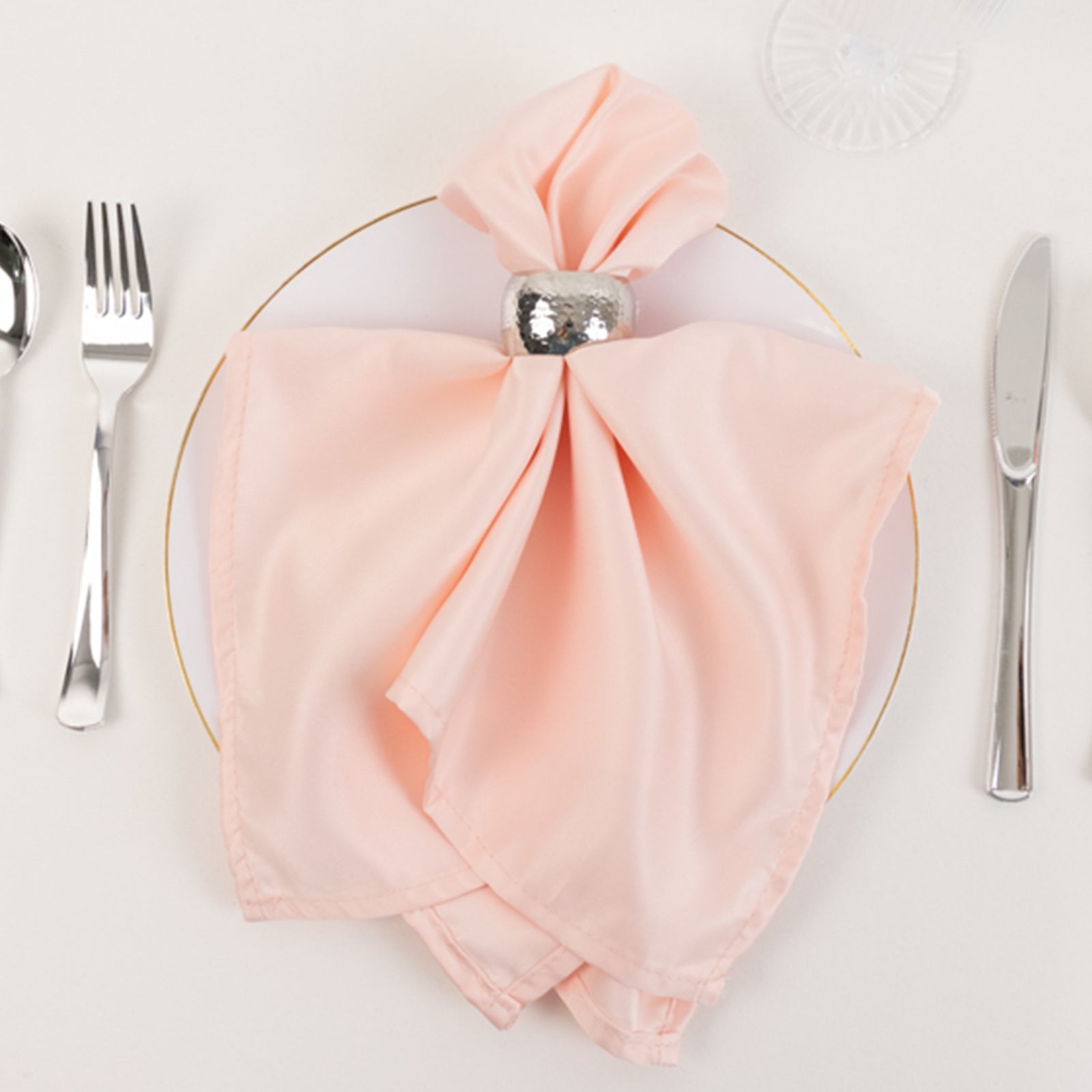 Blush satin napkins elegantly styled on a dinner plate.
