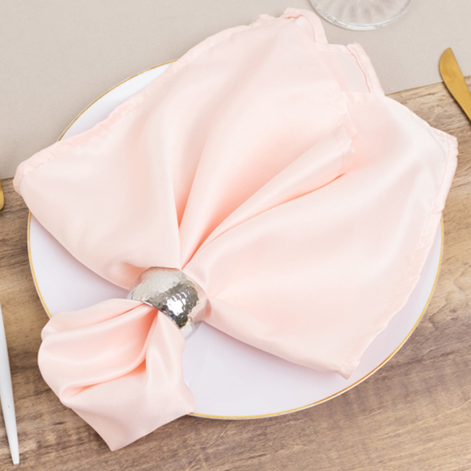 Blush satin napkins elegantly arranged on a plate.