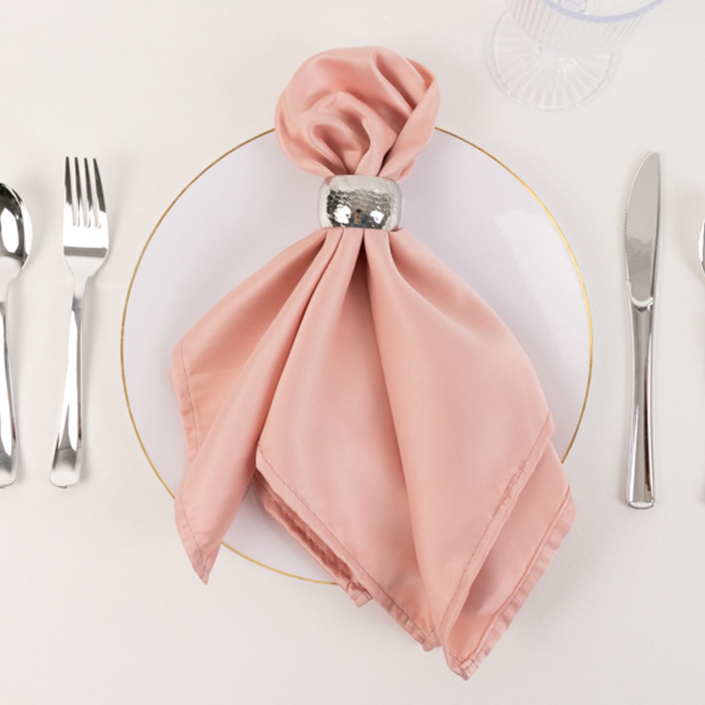 Dusty rose satin napkins elegantly arranged on a dining plate.
