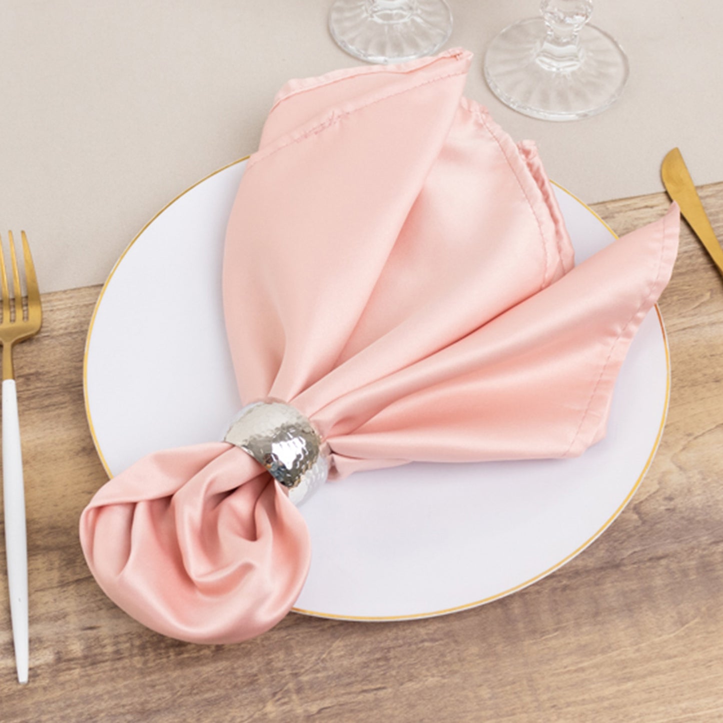 Dusty rose satin napkin elegantly arranged on a white plate.