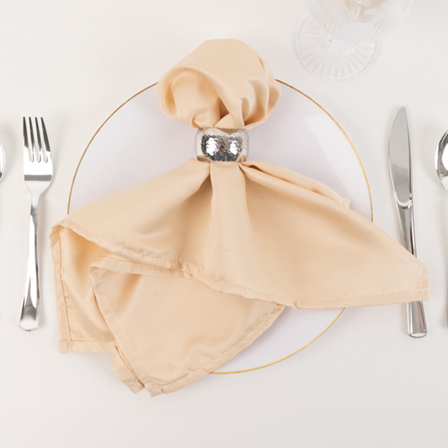Beige satin napkin elegantly arranged on a dining plate.