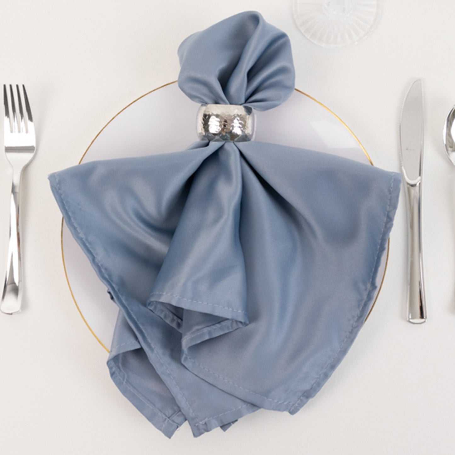 Dusty blue satin napkin elegantly arranged on a plate.