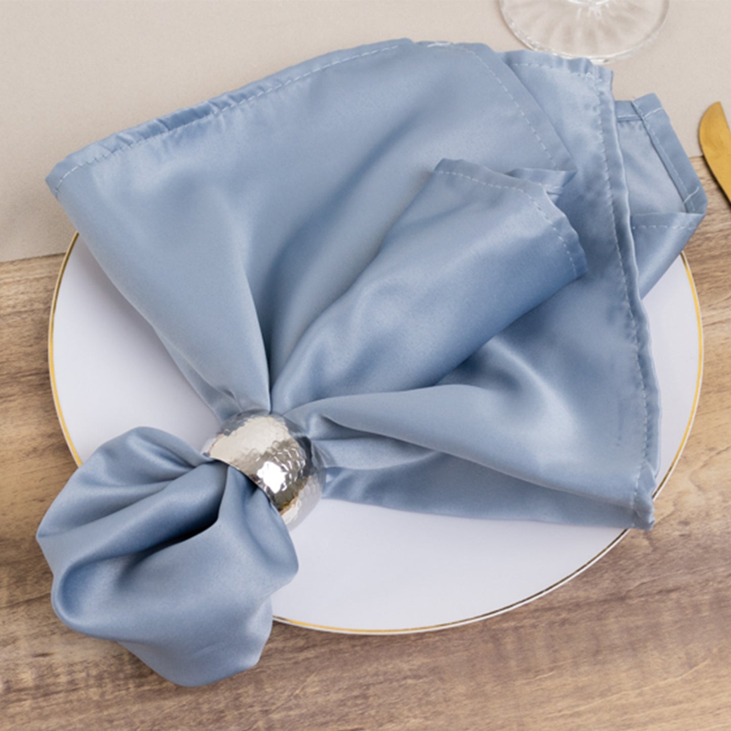 Dusty blue satin napkins on a plate, elegantly arranged for dining.