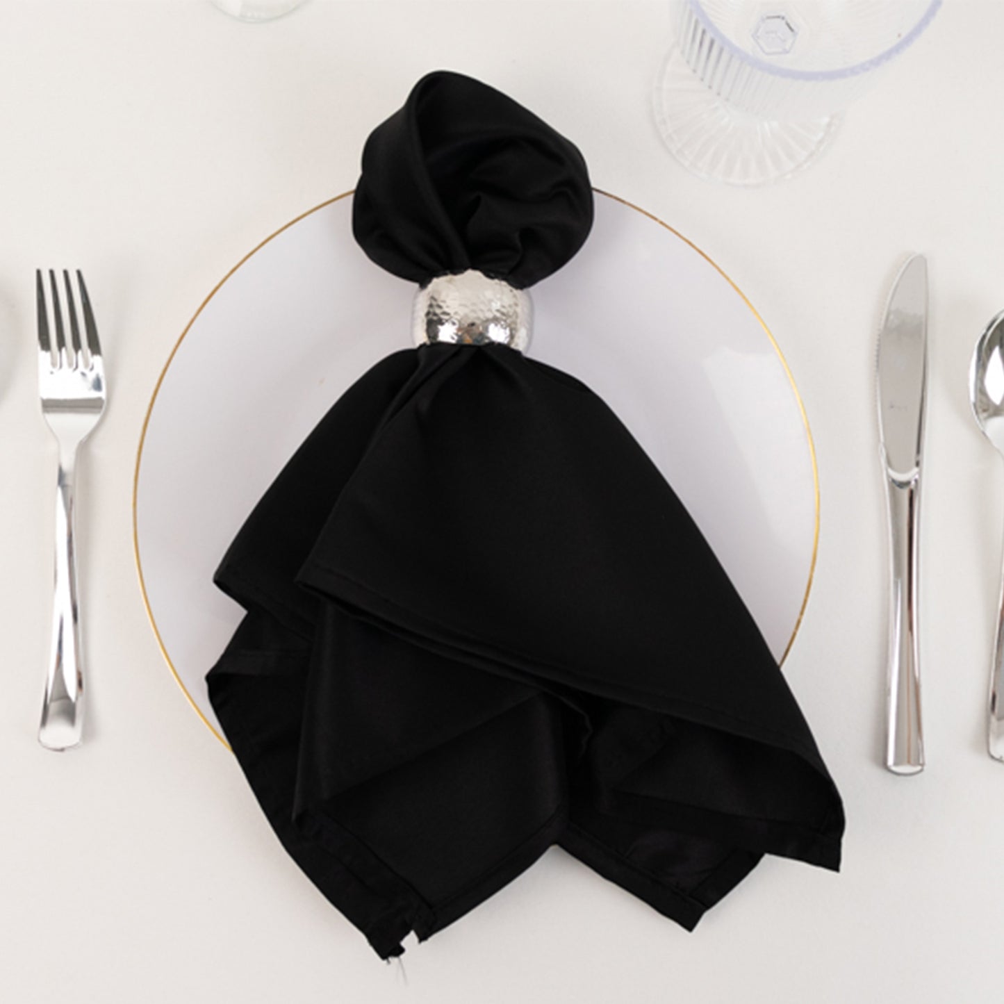 Black satin napkin elegantly arranged on a plate setting.