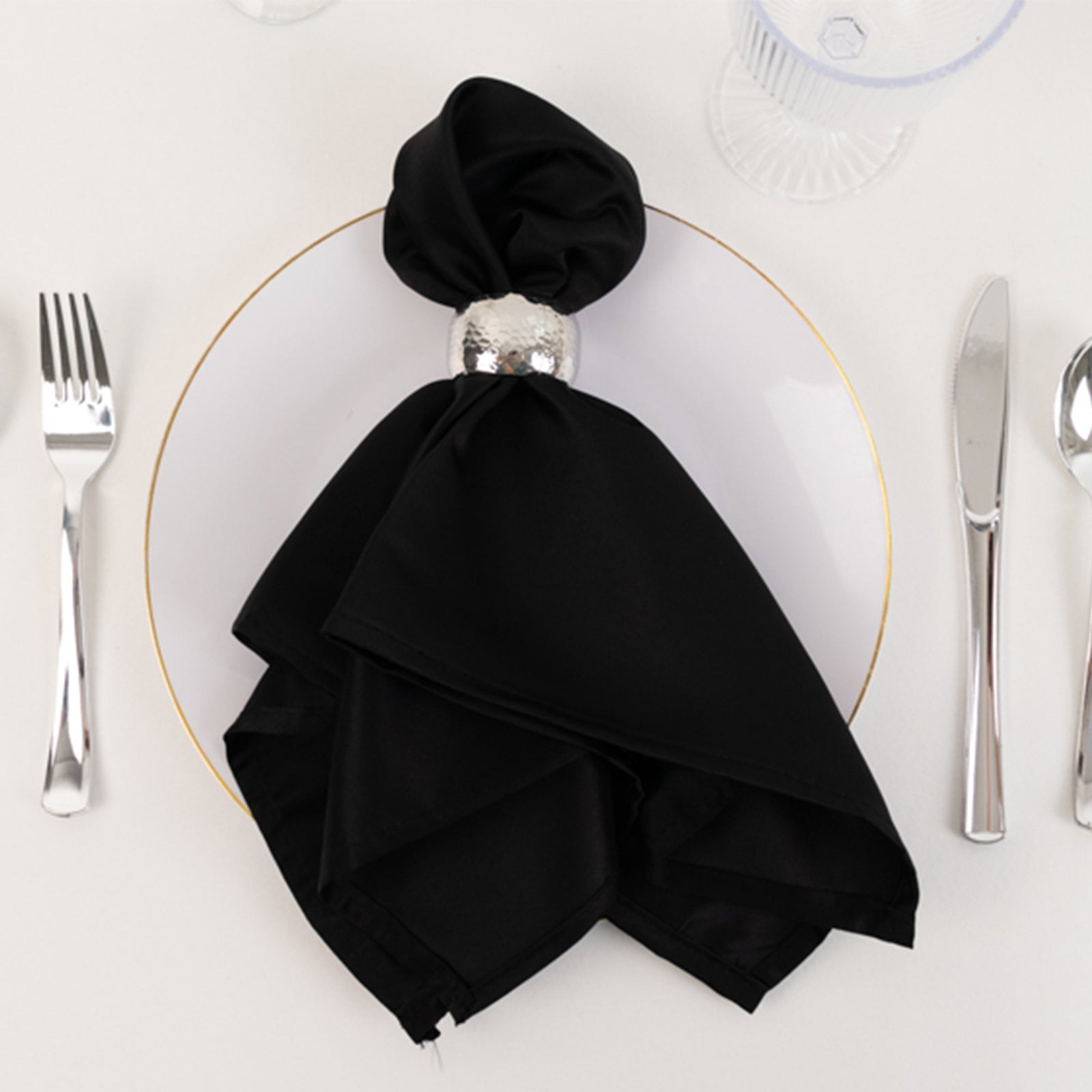 Black satin napkin elegantly arranged on a plate setting.