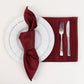 Burgundy satin napkins elegantly arranged on a table setting.