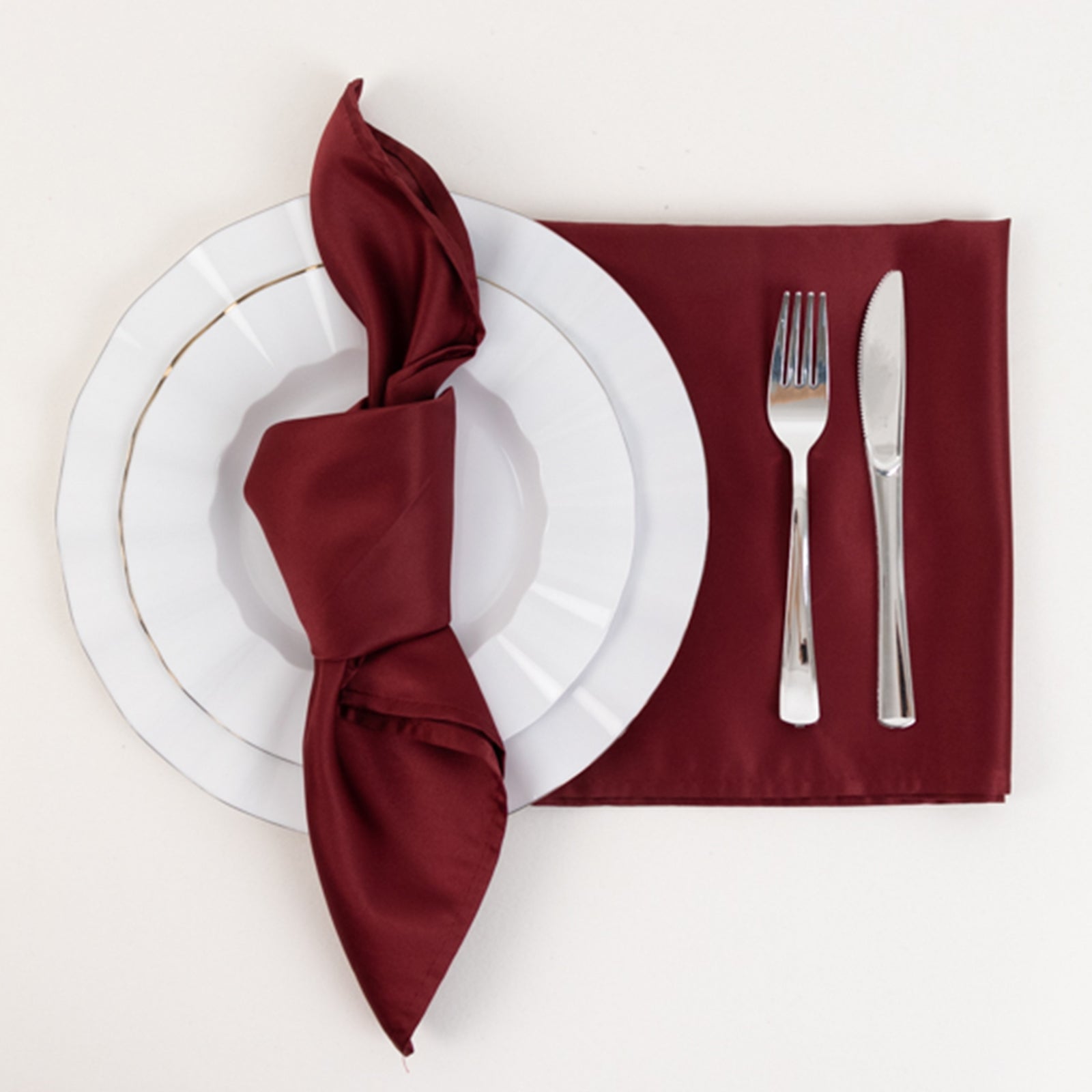 Burgundy satin napkins elegantly arranged on a table setting.