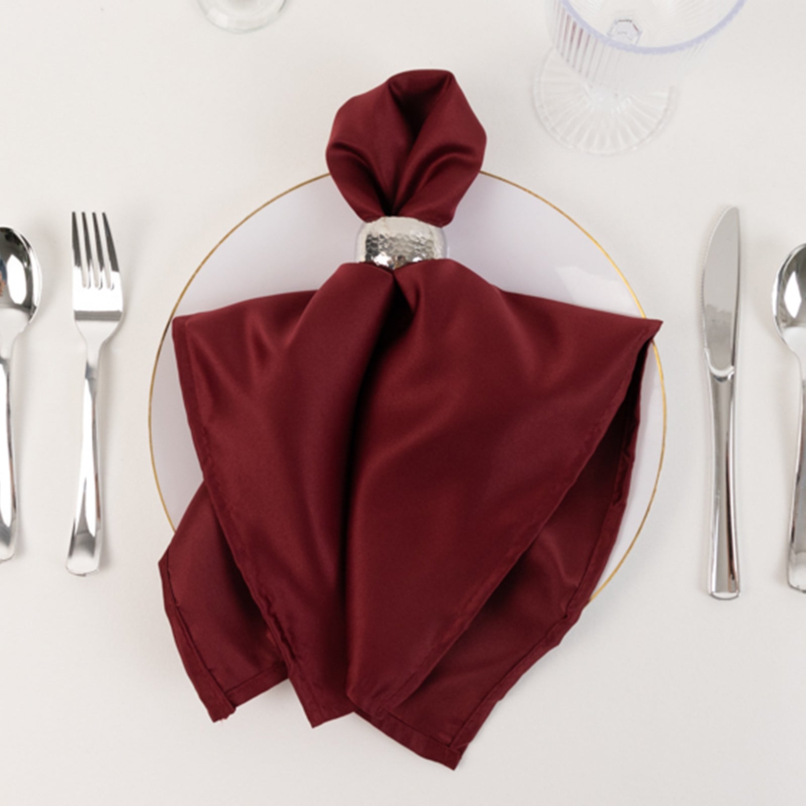 Burgundy satin napkin elegantly folded on a plate.
