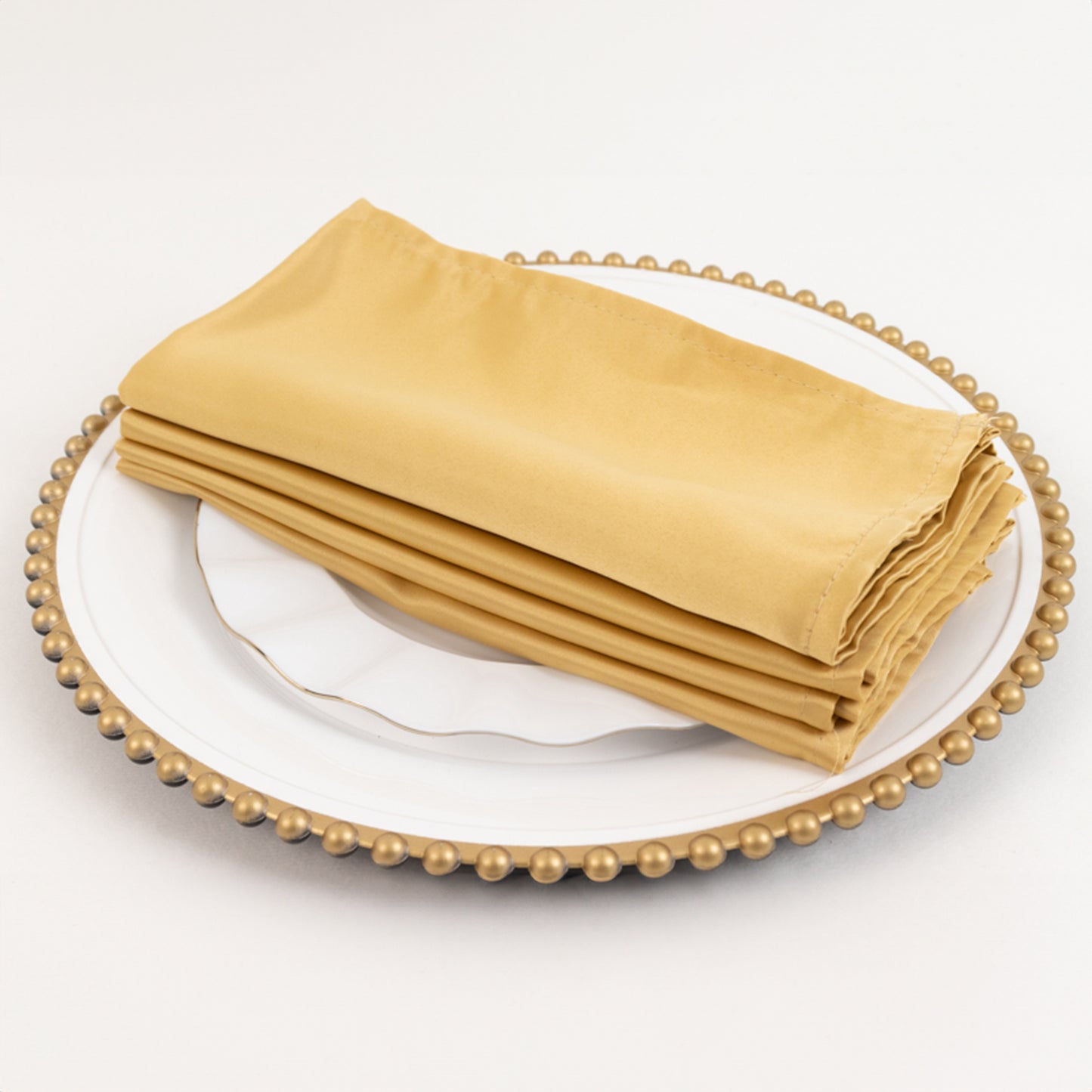 Champagne satin napkins on a decorative plate.