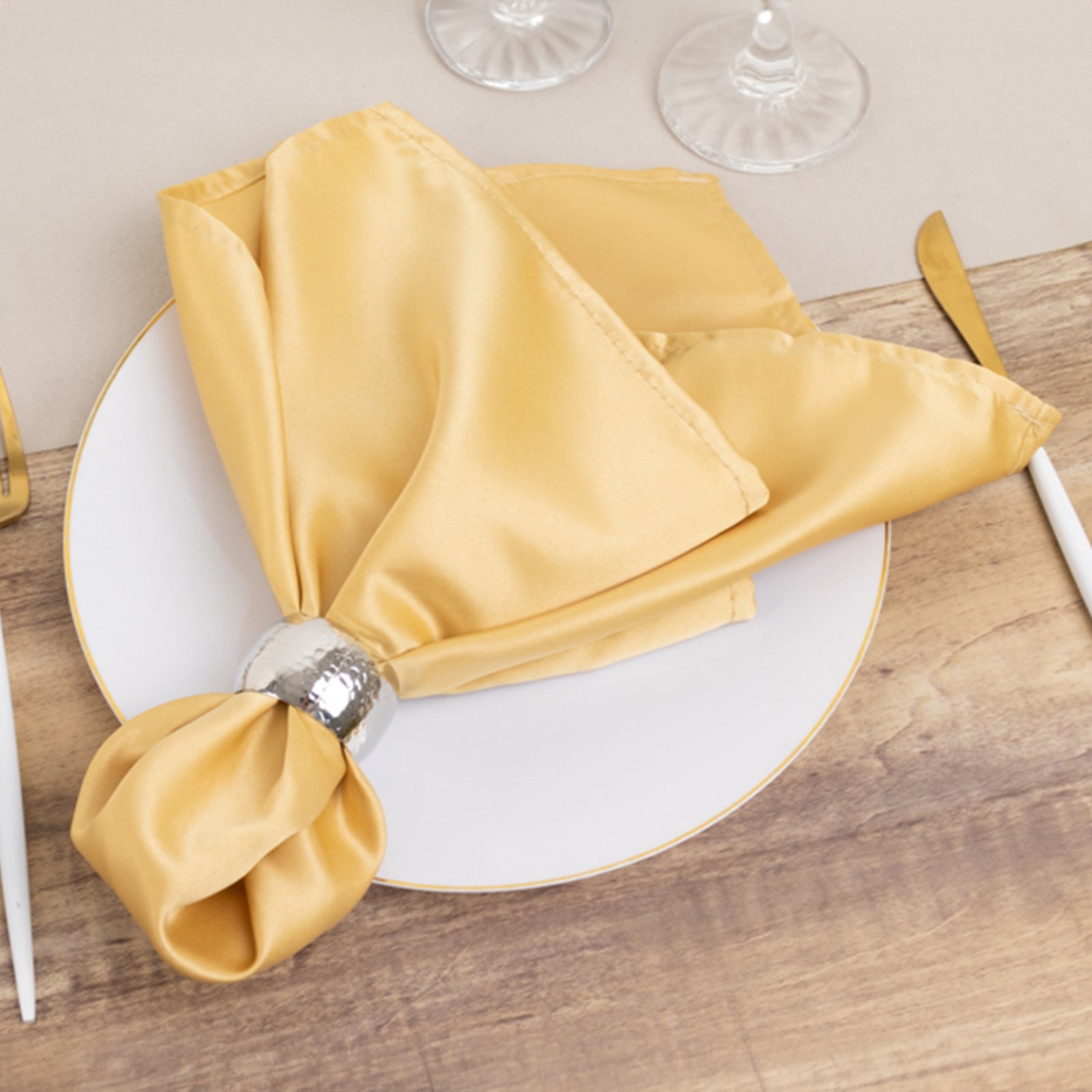 Champagne satin napkins on a plate, elegantly folded and styled.