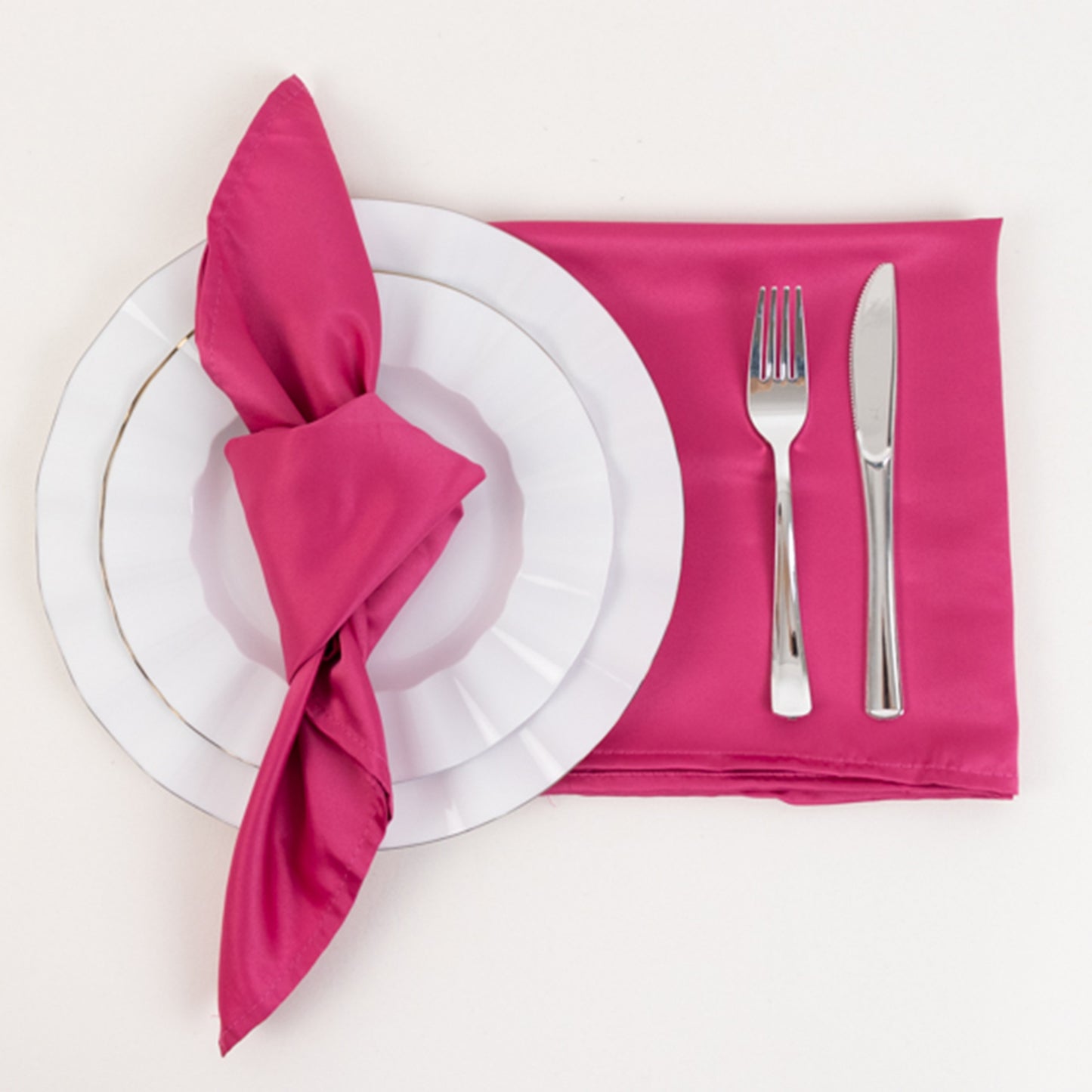 Fuchsia satin napkin on a table setting with plate and cutlery.