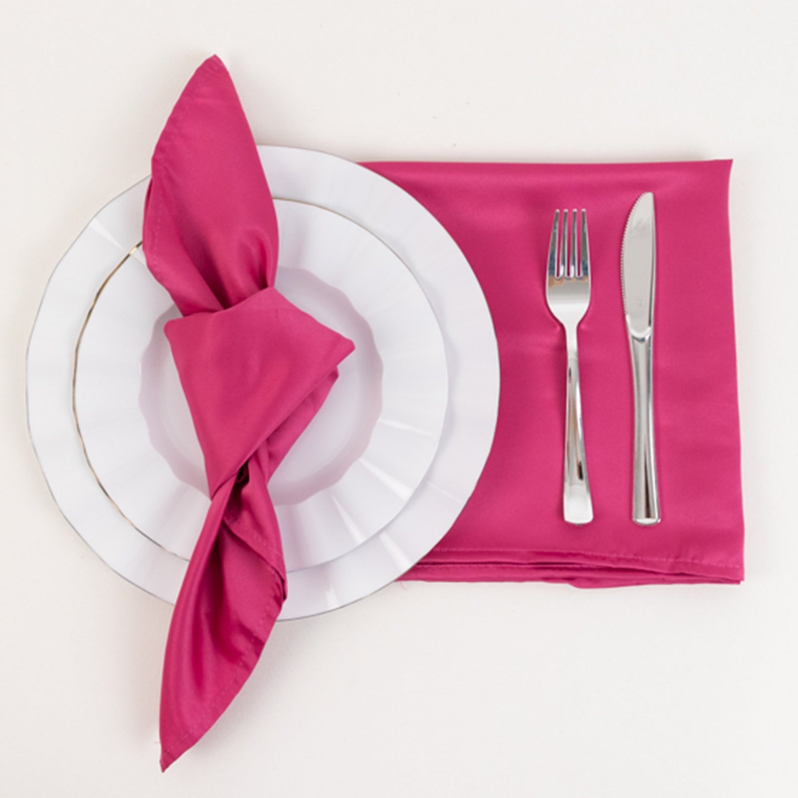 Fuchsia satin napkin on a table setting with plate and cutlery.