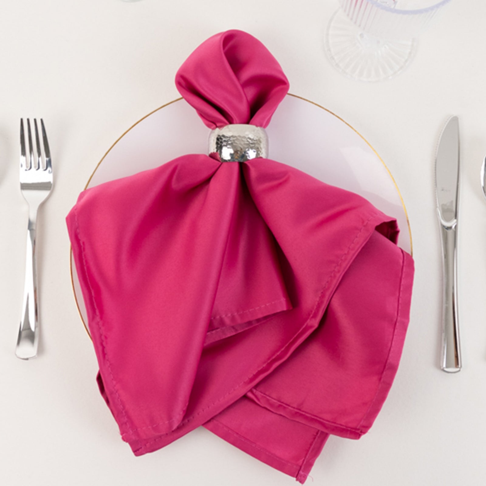Fuchsia satin napkins elegantly styled on a dinner plate.