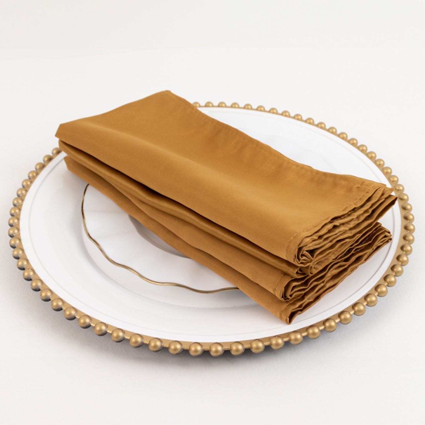 Gold satin napkins, 20"x20", in a pack of 5, elegantly stacked on a plate.