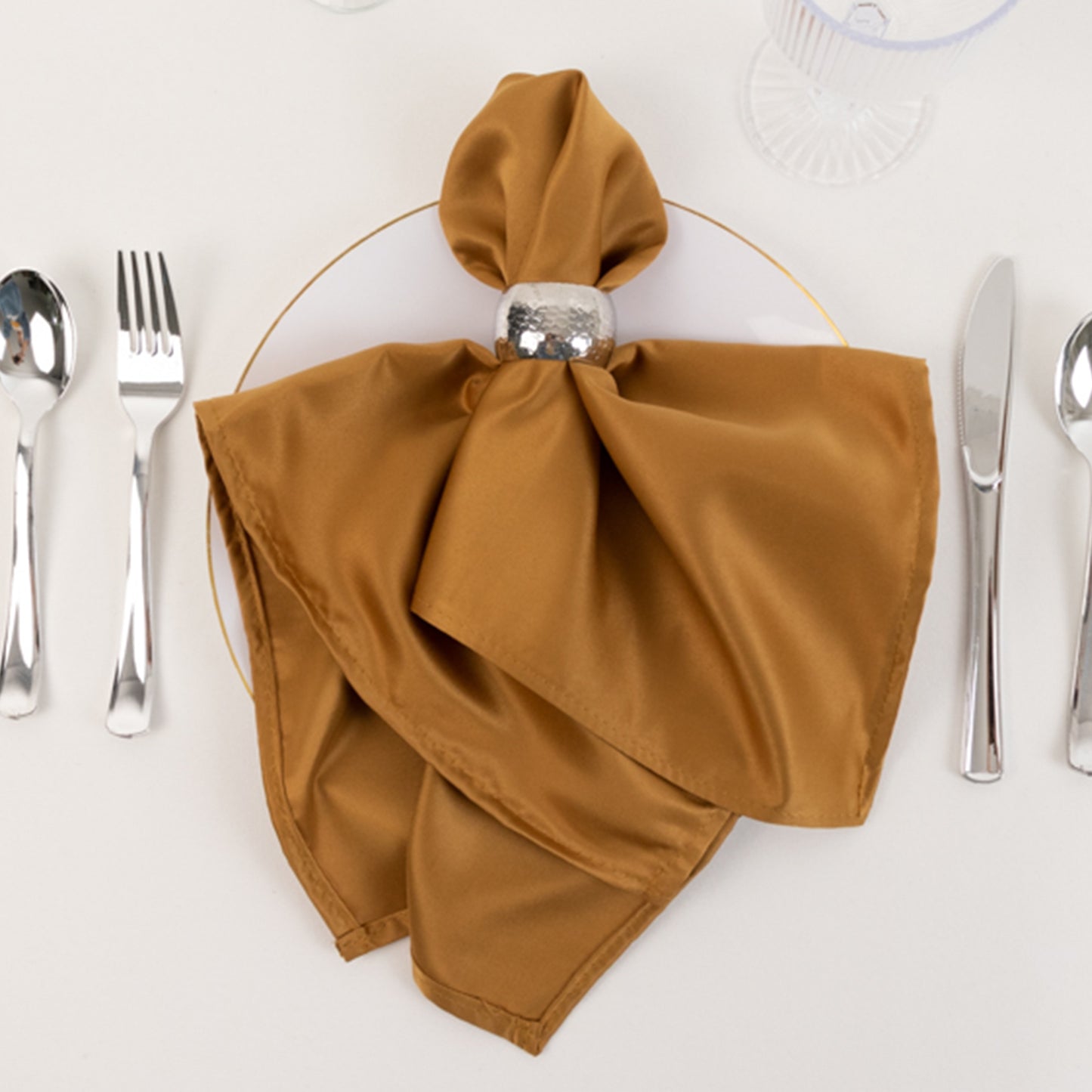 Gold satin napkin elegantly styled on a plate with silverware.