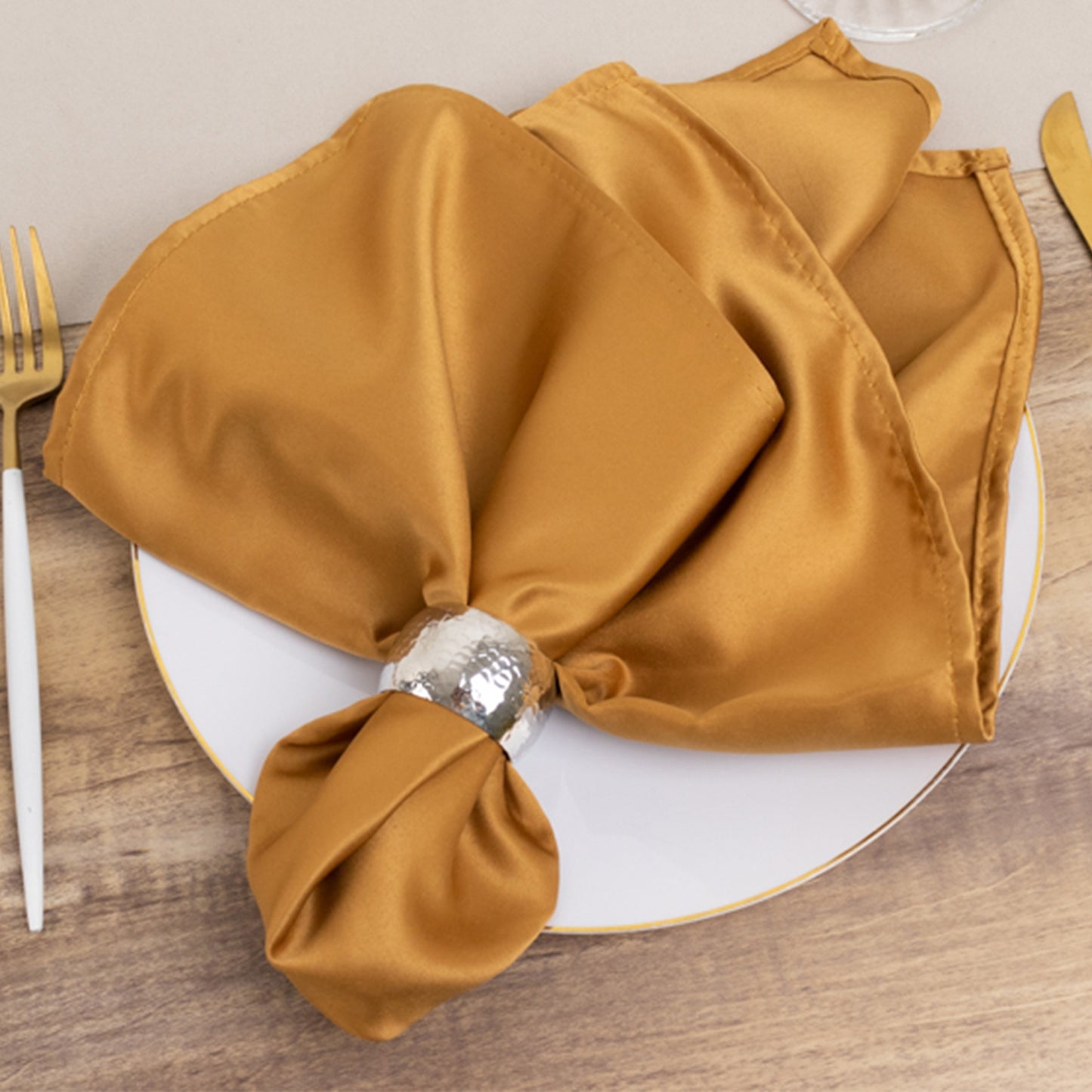 Gold satin napkins elegantly arranged on a plate.