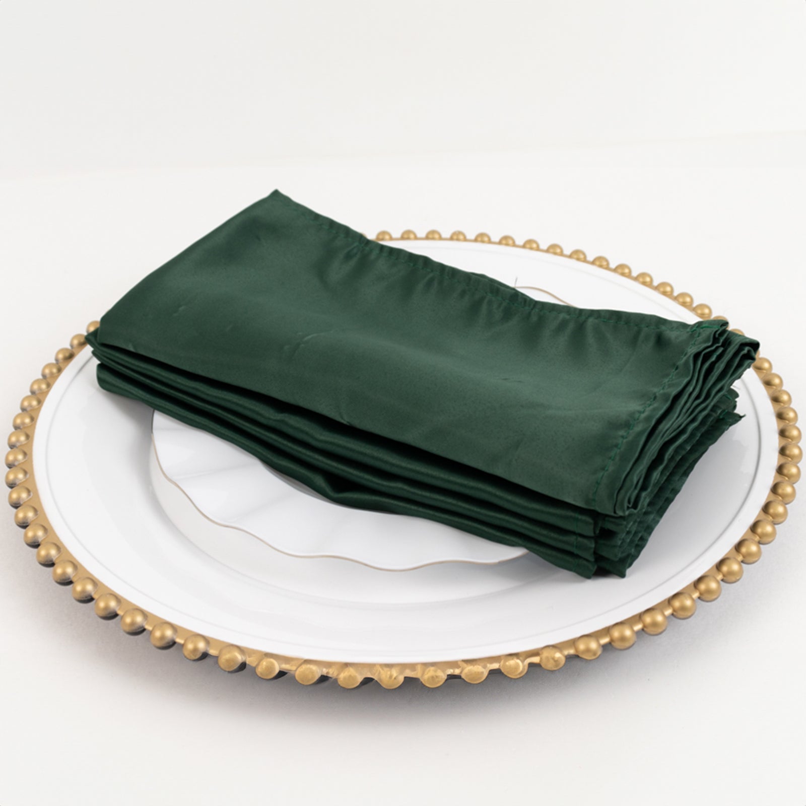 Hunter Emerald Green satin napkins stacked on a decorative plate.