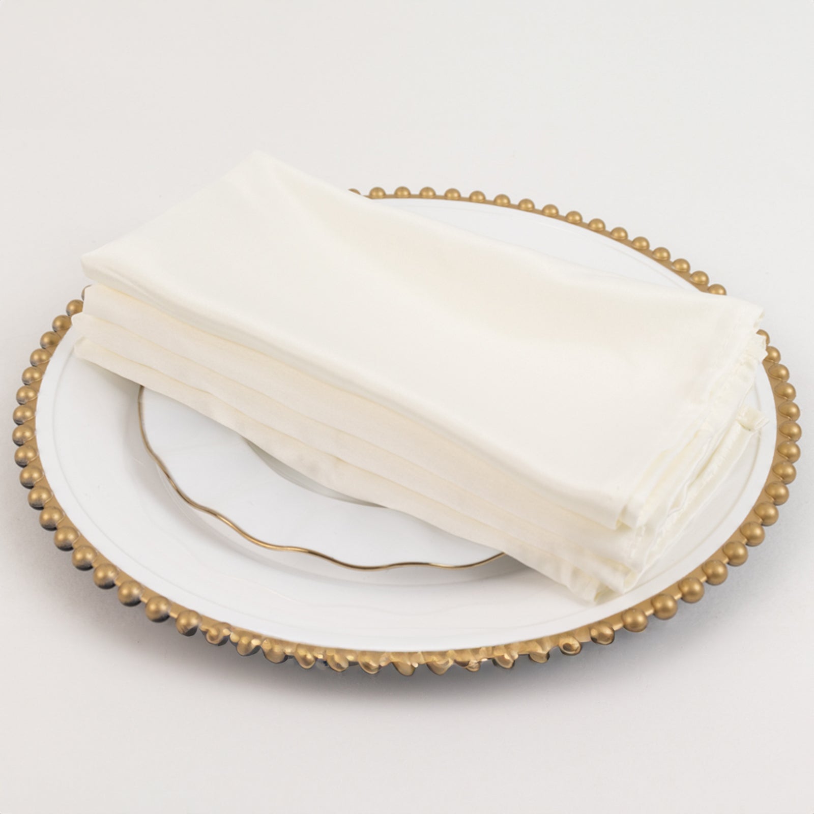 Ivory satin dinner napkins on a decorative plate.